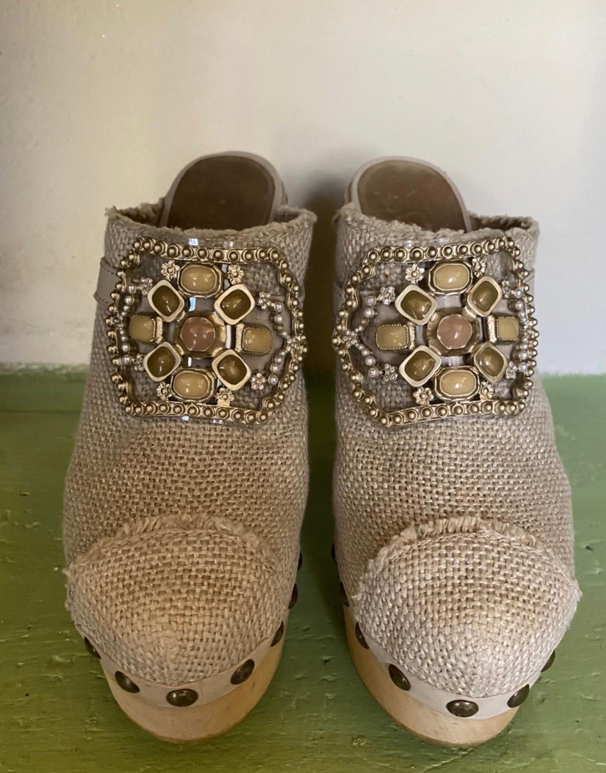 Chanel sabot, featuring wood wedges, beige-colored linen fabric , bronze-colored studs and Cabachon crystal pearls. it is Size 39, heel measures 14 cm, wedge measures 4 cm, in good condition, signs of wear as shown in the photos.