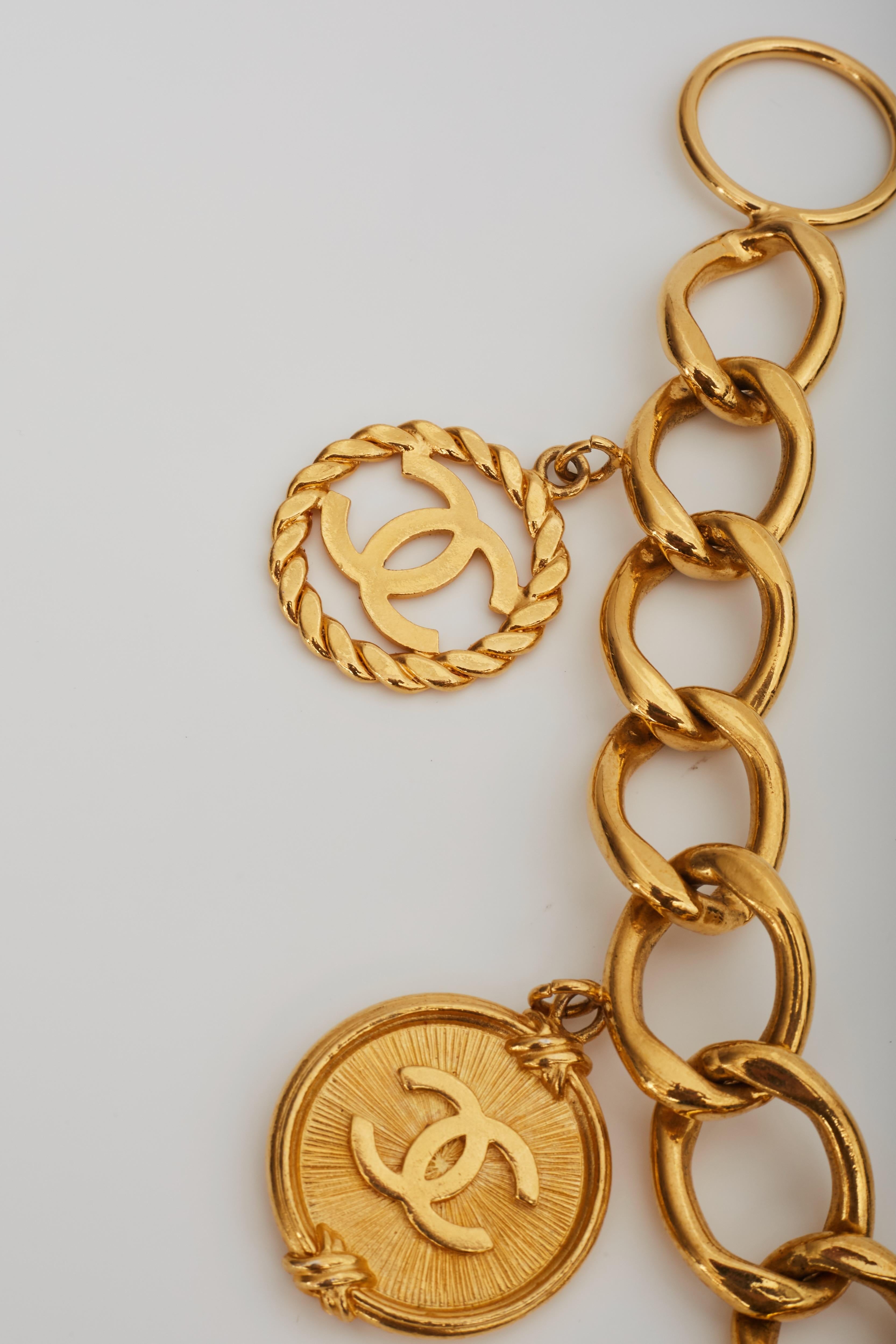 Chanel chance chain made of gold tone metal. Can be used as a belt or necklace. The chain features chunky links, 10 jumbo Chanel logo charms, hook closure, Chanel logo stamp with year 93 [logo] A and a heavy weight. Charms include cut out CC logos