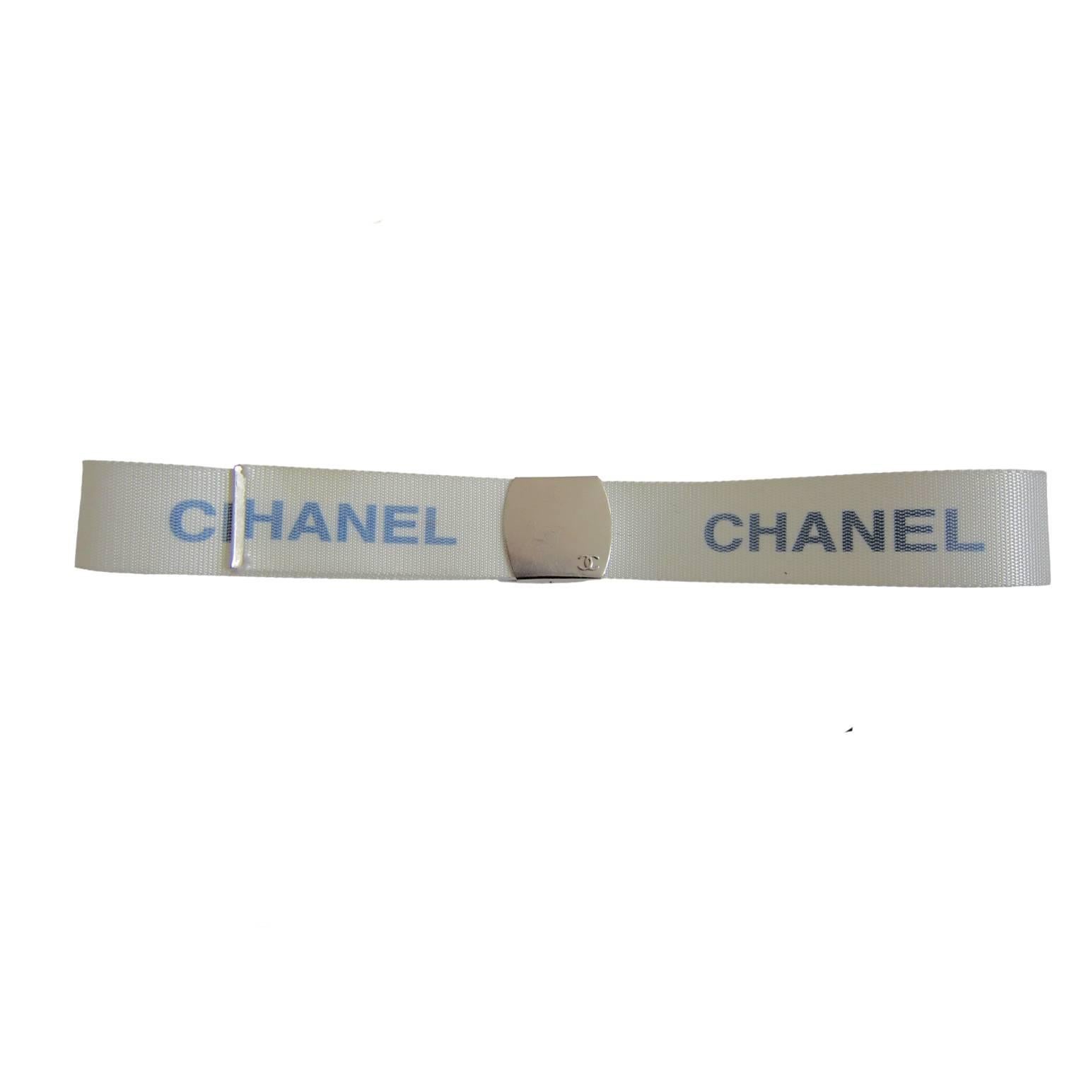 Chanel military style white nylon belt with blue logos from circa 90s. Silver tone metal logo buckleIt, can be adjusted to fit any waist size. 
Total length with buckle : 85. 5 cm