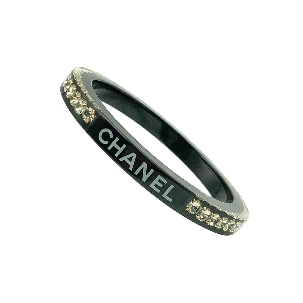A Chanel Logo Rhinestone Bangle. Featuring the iconic name CHANEL imprinted twice and beautifully interspersed with crystal chaton stones suspended within the resin glinting and glistening to perfection.
Since 1910 when Gabrielle 'Coco' Chanel