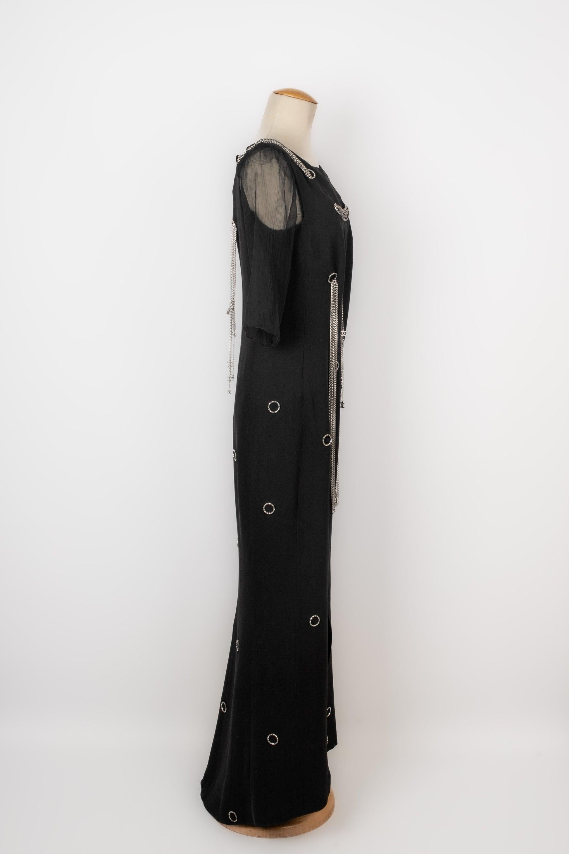 Chanel -(Made in France) Vestido largo de seda negra decorado con pedrería y cadenas de metal plateado. Talla 38FR indicada. Colección prêt-à-porter primavera-verano 2008 bajo la dirección artística de Karl Lagerfeld.

Más información:
Estado: Muy