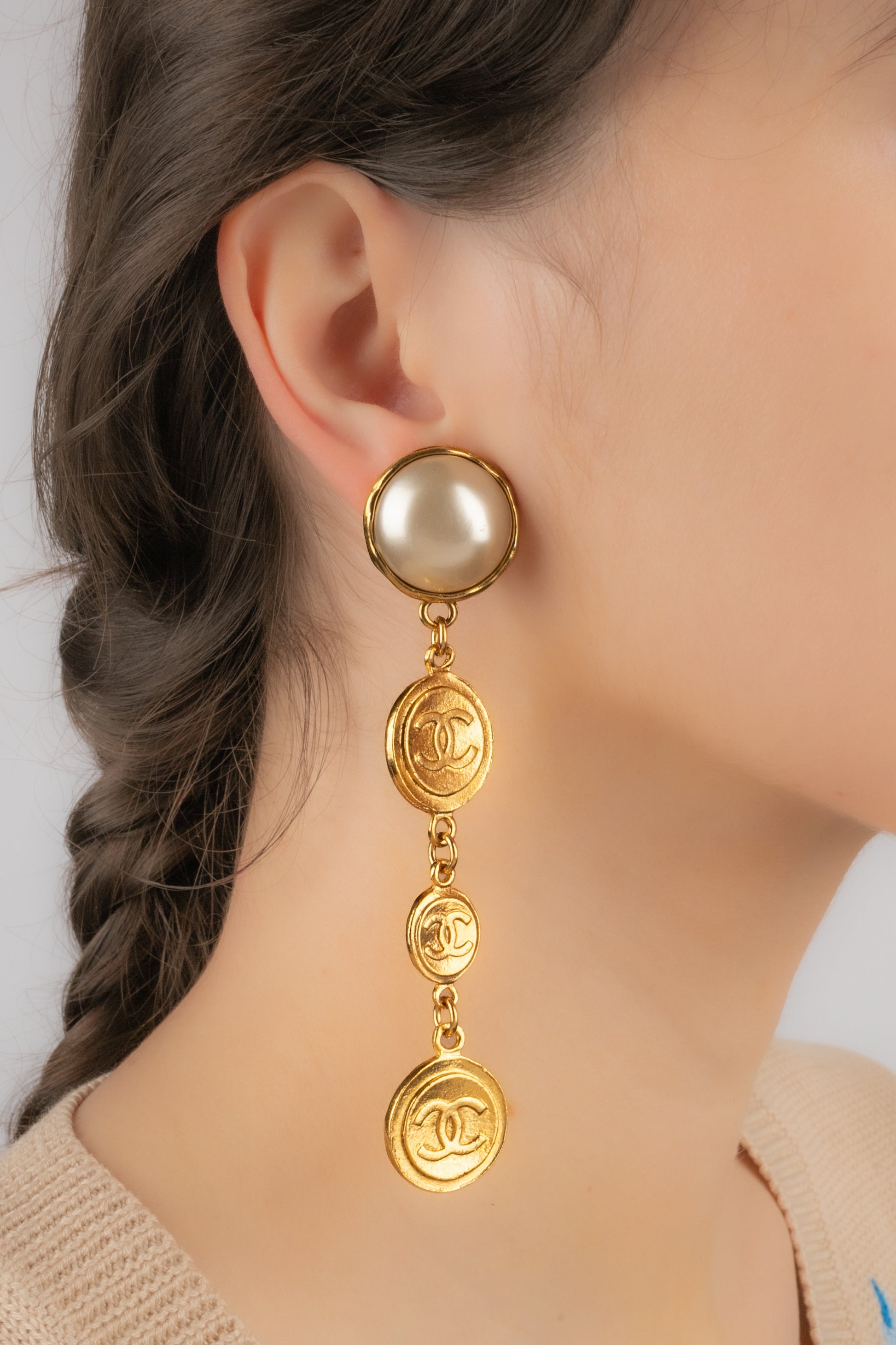 CHANEL - (Made in France) Long golden metal clip-on earrings with pearly cabochons. Jewelry from the 1990s.

Additional information:
Condition: Very good condition
Dimensions: Length: 10.5 cm

Seller Reference: BOB243
