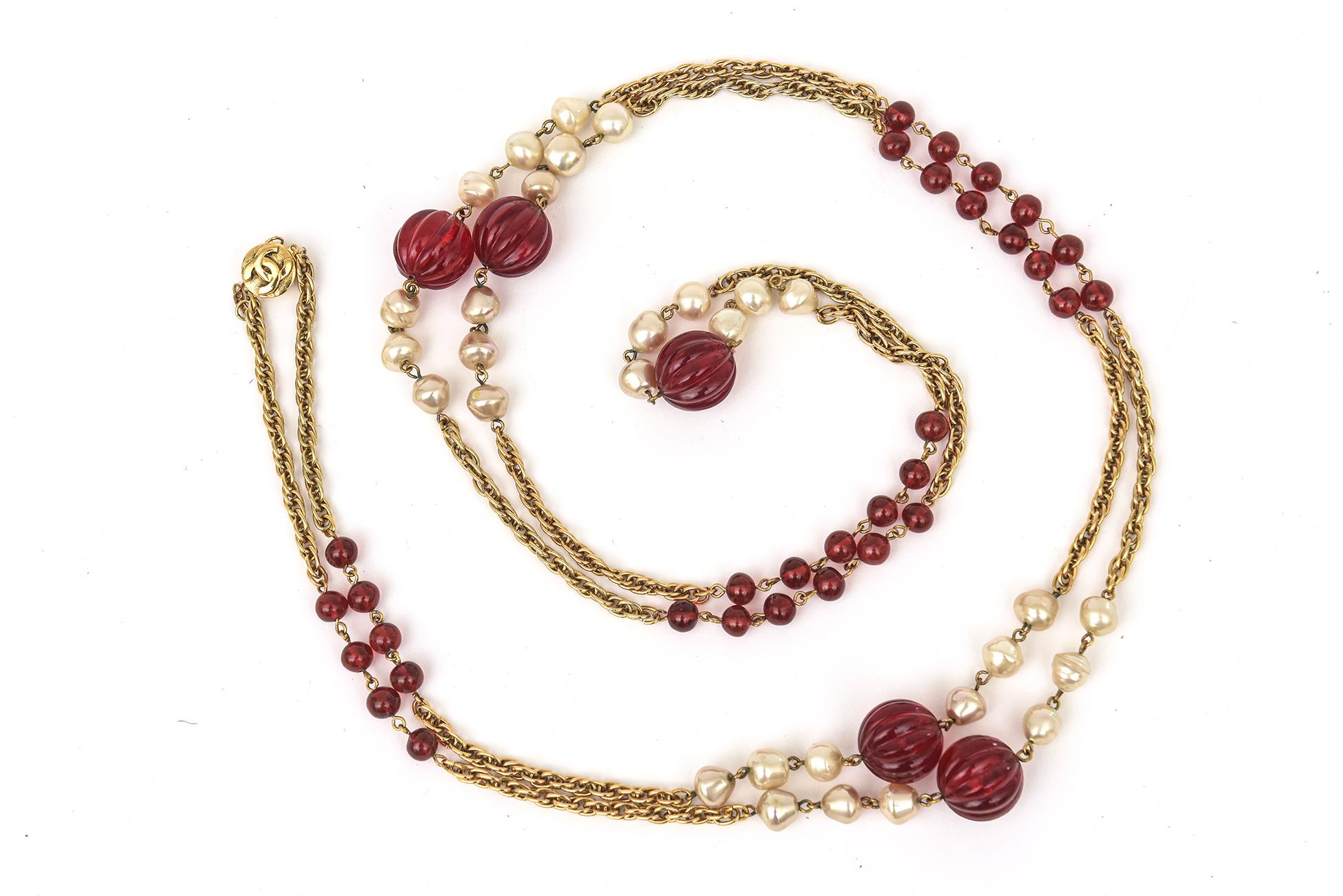 Ce fabuleux long collier Chanel sautoir vintage est composé de perles de verre rouge gripoix, de fausses perles intercalées le long de la chaîne à maillons en métal doré. Les perles de verre rouges sont de deux tailles différentes. Il peut