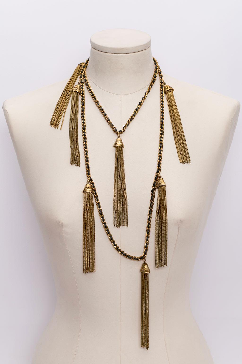 Chanel - (Made in France) Long necklace made of a gilted metal chain entwined with black leather, and adorned with tassels. Fall-Winter 1994 collection.

Additional information:
Condition: Very good condition
Dimensions: Length: 122 cm (48.03