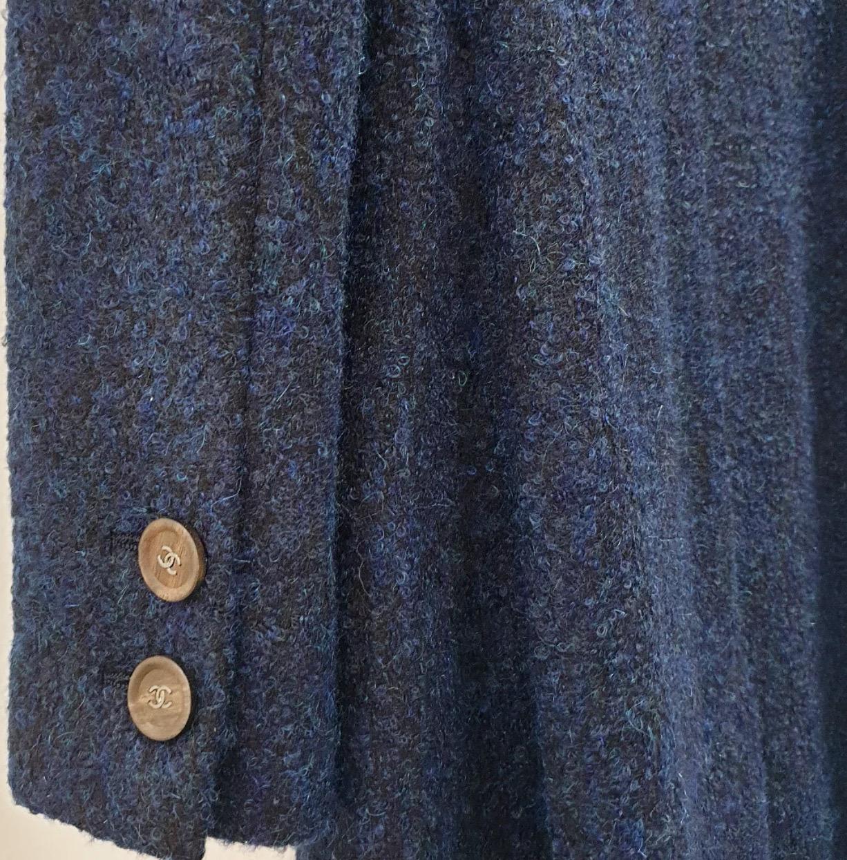Stunning Chanel long wool coat in a sophisticated navy blue. This timeless piece features elegant metallic CC logo wooden buttons, adding a touch of luxury. The coat is a size 36. Please refer to the photo for approximate measurements (laid flat,