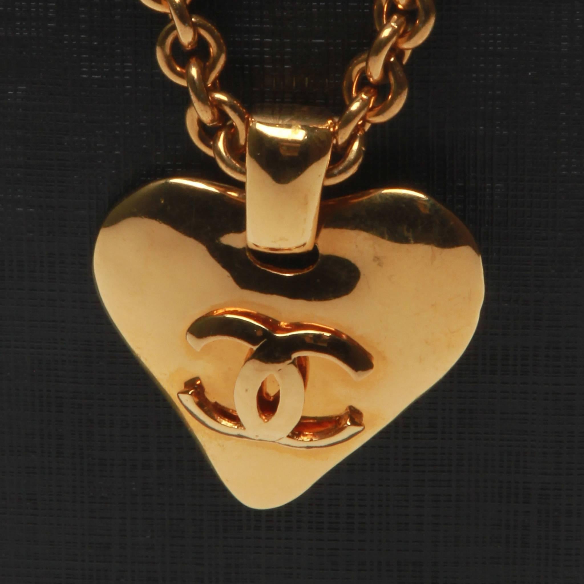 Chanel love heart interlocking CC pendant necklace in gold-tone metal with rolo chain and spring ring fastening.

Stamped 93 P 