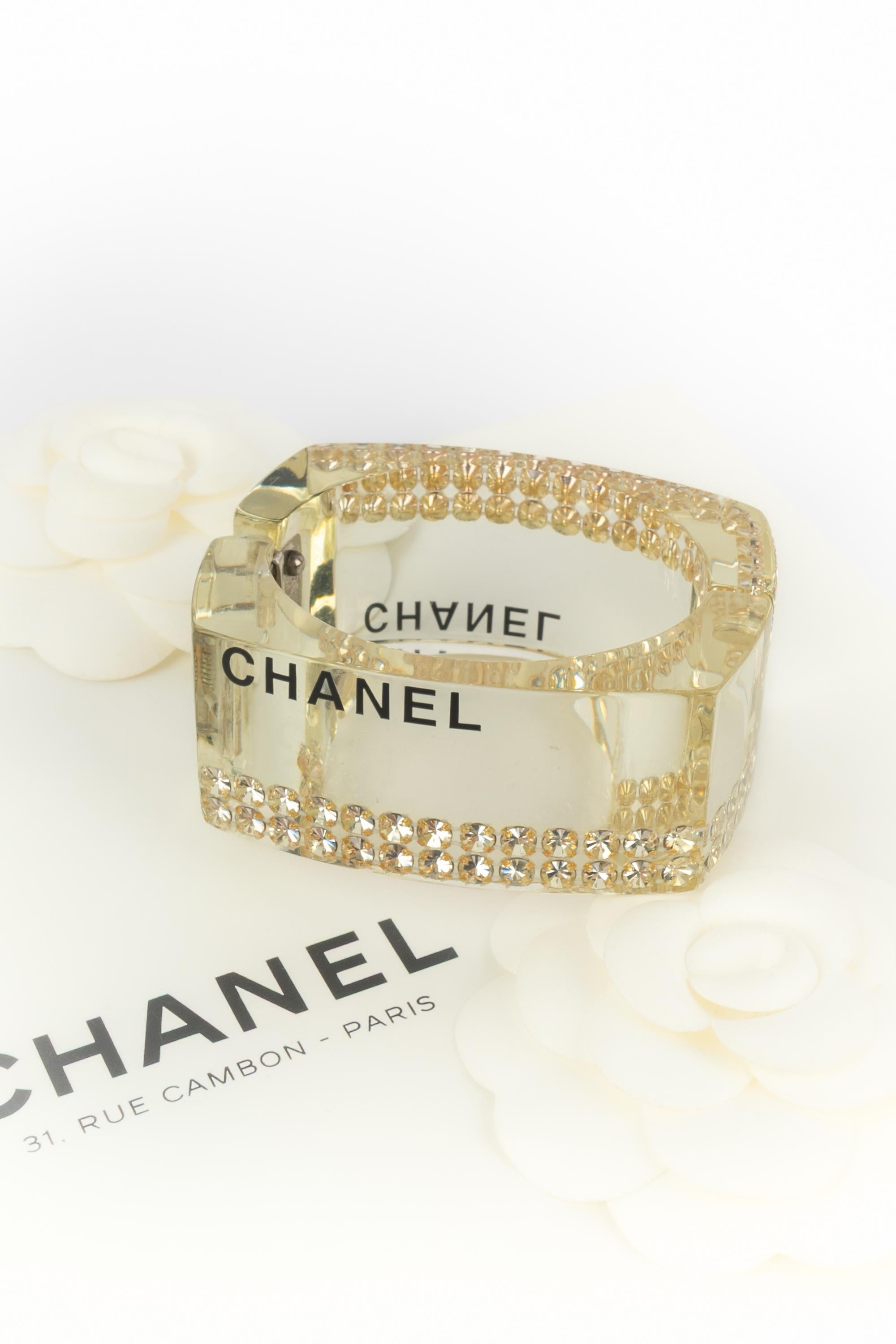 Chanel - (Made in France) Bracciale in lucite con strass incastonati. Collezione primavera-estate 2005 sotto la direzione artistica di Karl Lagerfeld.

Condizioni:
Ottime condizioni

Dimensioni:
Circonferenza: 16 cm - Larghezza: 3 cm

SKU:BRAB50