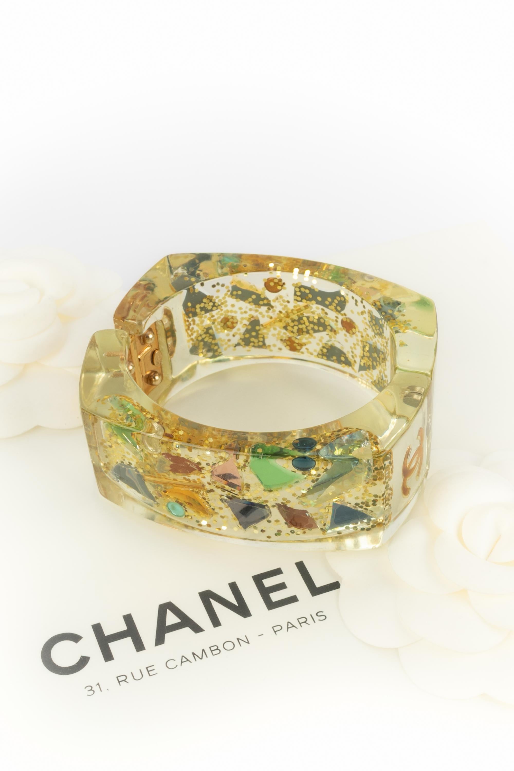 Chanel - (Made in France) Bracciale in lucite con paillettes ed elementi decorativi. Collezione primavera-estate 2003 sotto la direzione artistica di Karl Lagerfeld.

Condizioni:
Ottime condizioni

Dimensioni:
Circonferenza: 16 cm - Altezza: 3