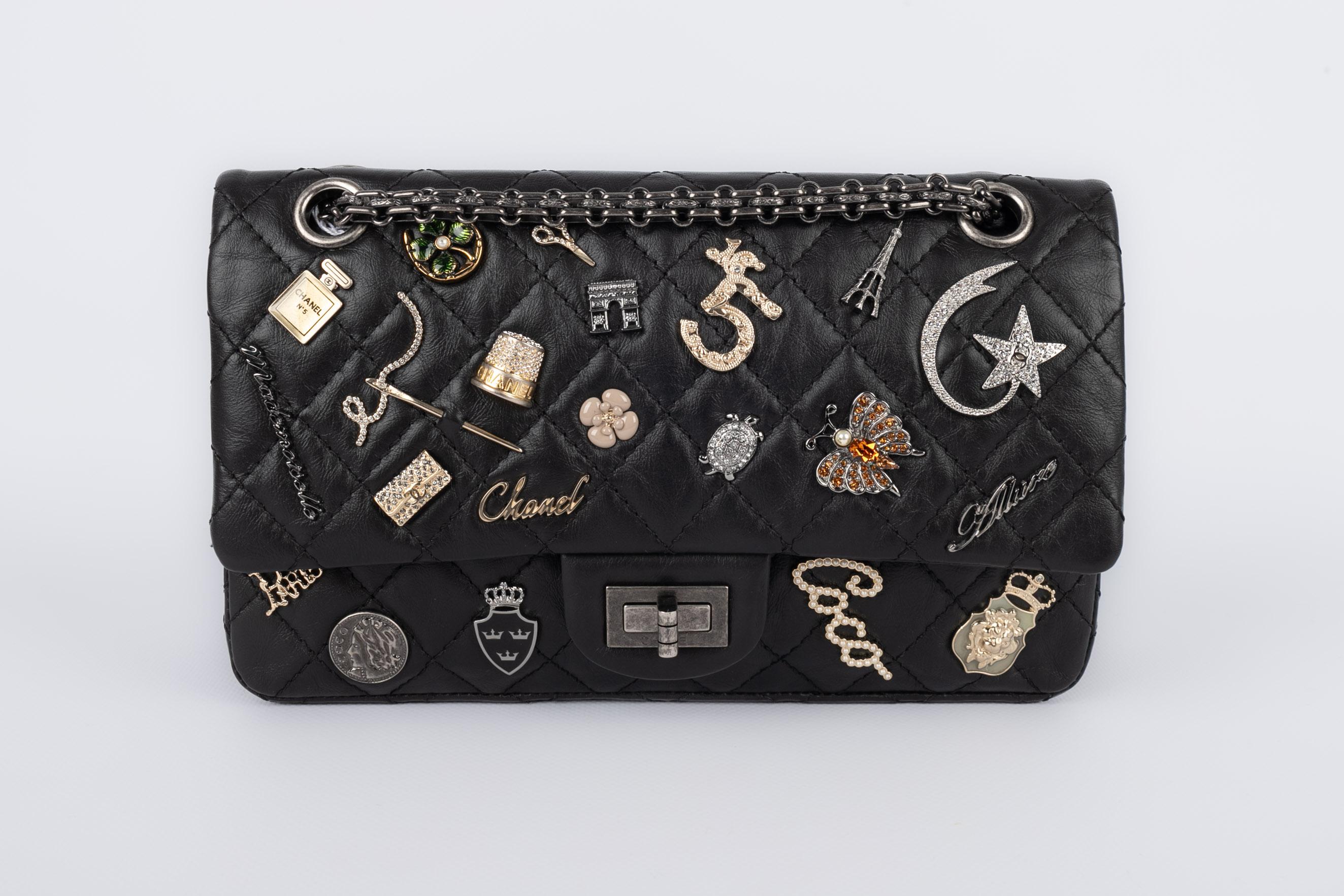 CHANEL - (Made in France) Black quilted leather 2.55 design bag enlivened with enamel and rhinestone ornamented metal charms. Dark-silvery metal elements. 2014/2015 Collection.

Condition:
Very good condition

Dimensions:
Length: 24 cm - Height: 15