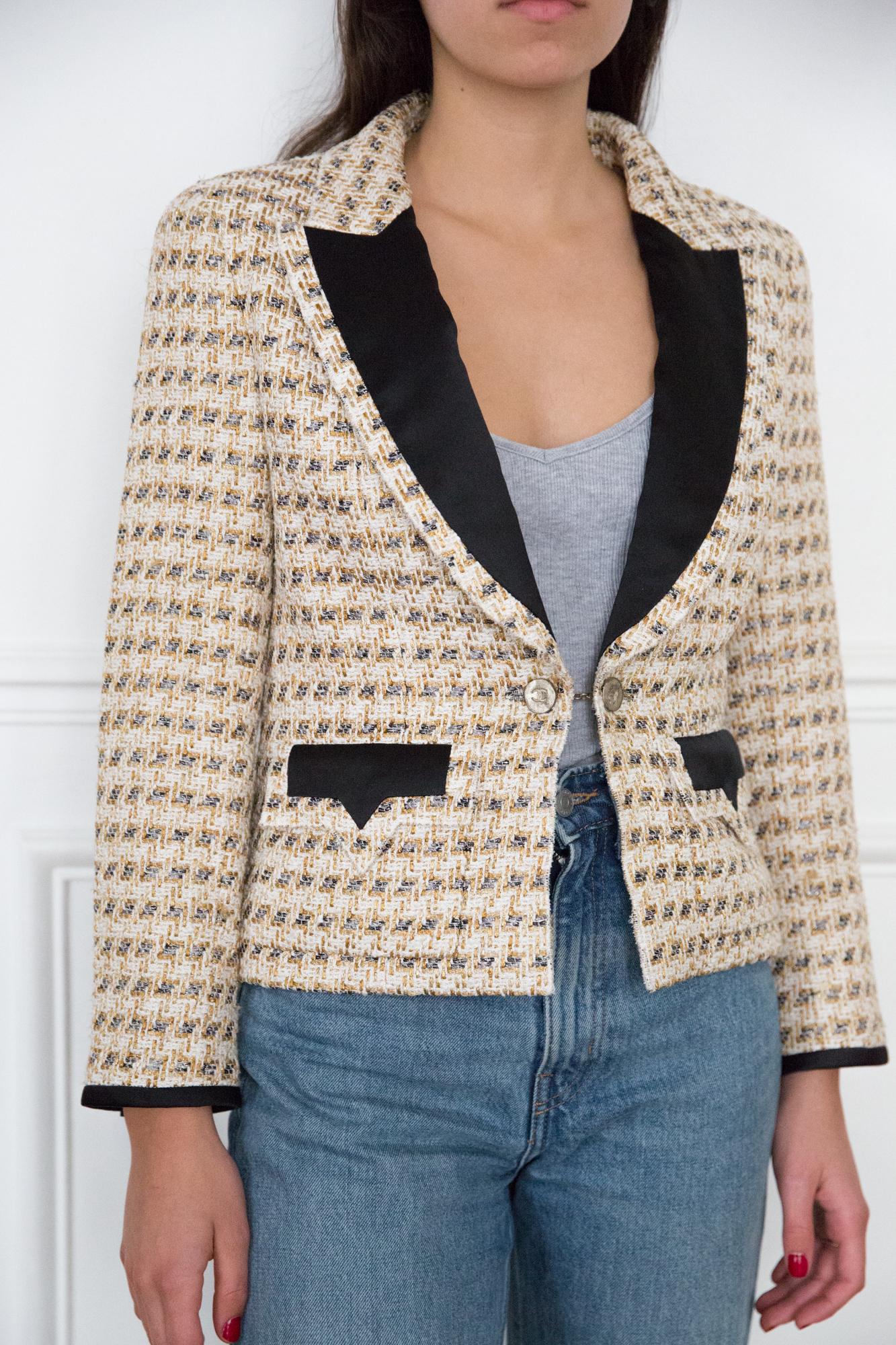 Chanel lurex tweed wool boucle jacket featuring a short fitted shape, a tweed boucle fabric with metallic threading, logo button cuffs, front flap pockets, a straight hem, a silk lining, contrasting lapels, cropped long sleeves and a single logo