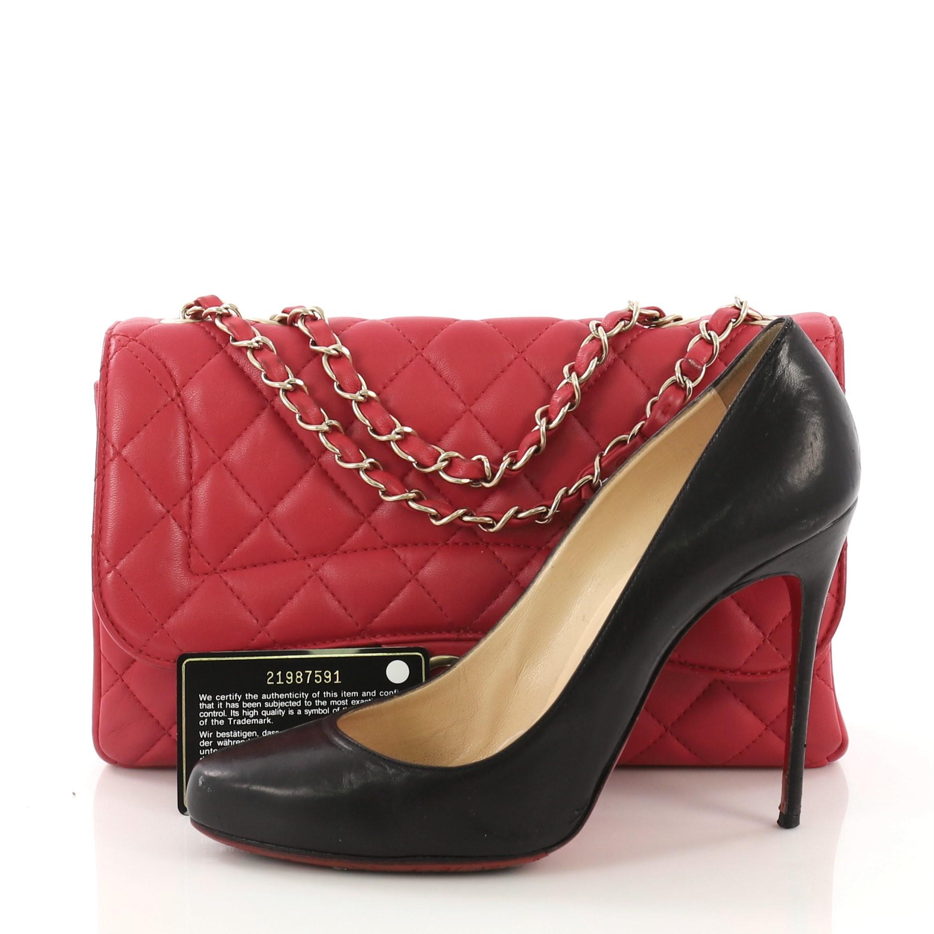 This Chanel Mademoiselle Chic Flap Bag Quilted Lambskin Medium, crafted from dark pink quilted lambskin, features woven-in leather chain straps, an exterior back slip pocket, and matte gold-tone hardware. Its turn-lock closure opens to a red fabric