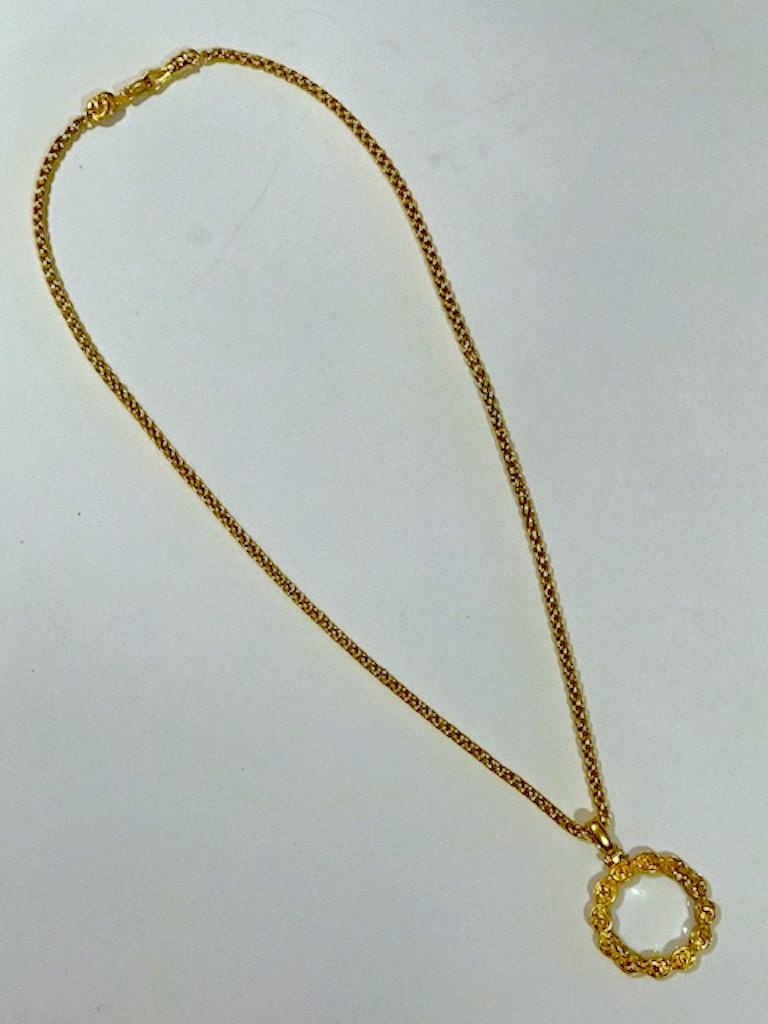 A wonderful Chanel wheat chain link necklace with magnifying lens pendant necklace. The glass lens is set into a frame of twelve ovals each with the iconic Chanel CC logo. The necklace closure is hook and eye. The pendant measures 2 inches wide and
