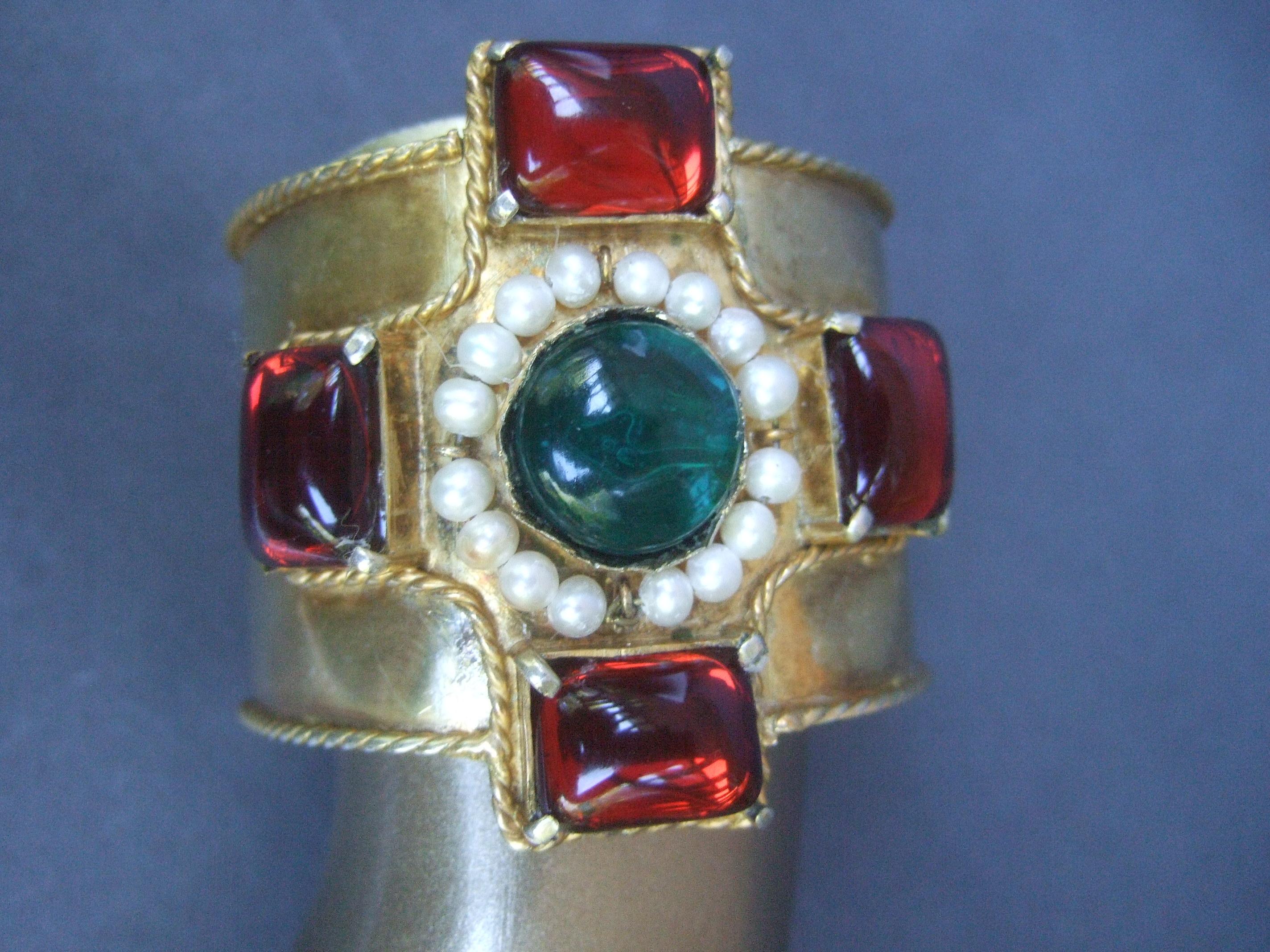 Chanel Maison Gripoix Byzantine style poured glass wide gilt metal cuff bracelet in Chanel box c 1984
The opulent Chanel wide gilt metal cuff bracelet is adorned with a cluster of deep red smooth poured glass translucent rectangular shaped stones in