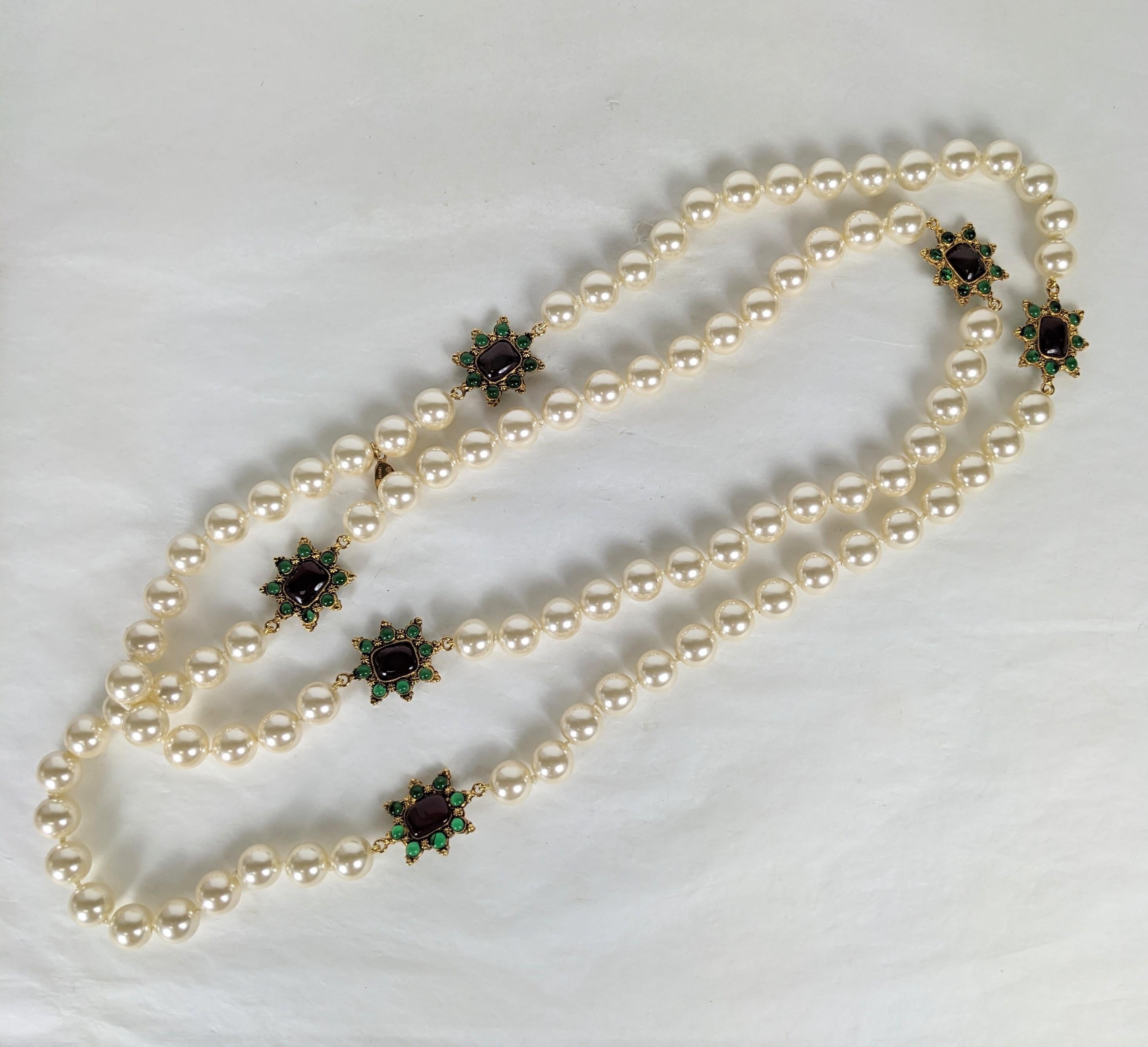 Ravissant collier Chanel en fausses perles sans fin à maillons byzantins. Composée de fausses perles en verre nouées à la main en continu avec des stations de cabochons réversibles en bronze doré, émaillées de rubis et d'émeraudes, réalisées à la