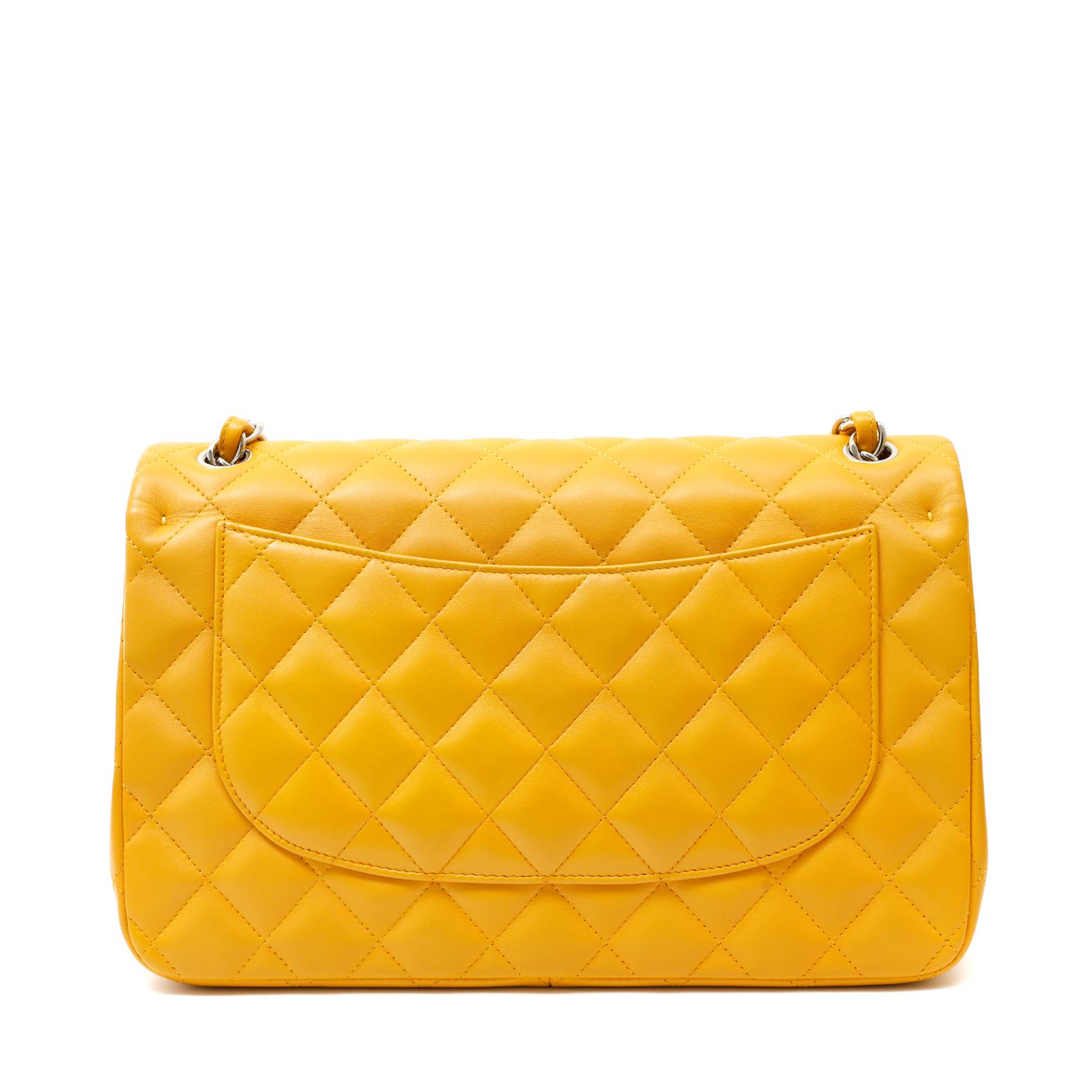 This authentic Chanel Marigold Lambskin Jumbo Classic is in pristine condition. A vibrant hue of golden yellow makes it a must have for any collection.  
Marigold lambskin is quilted in signature Chanel diamond pattern.  Silver interlocking CC twist