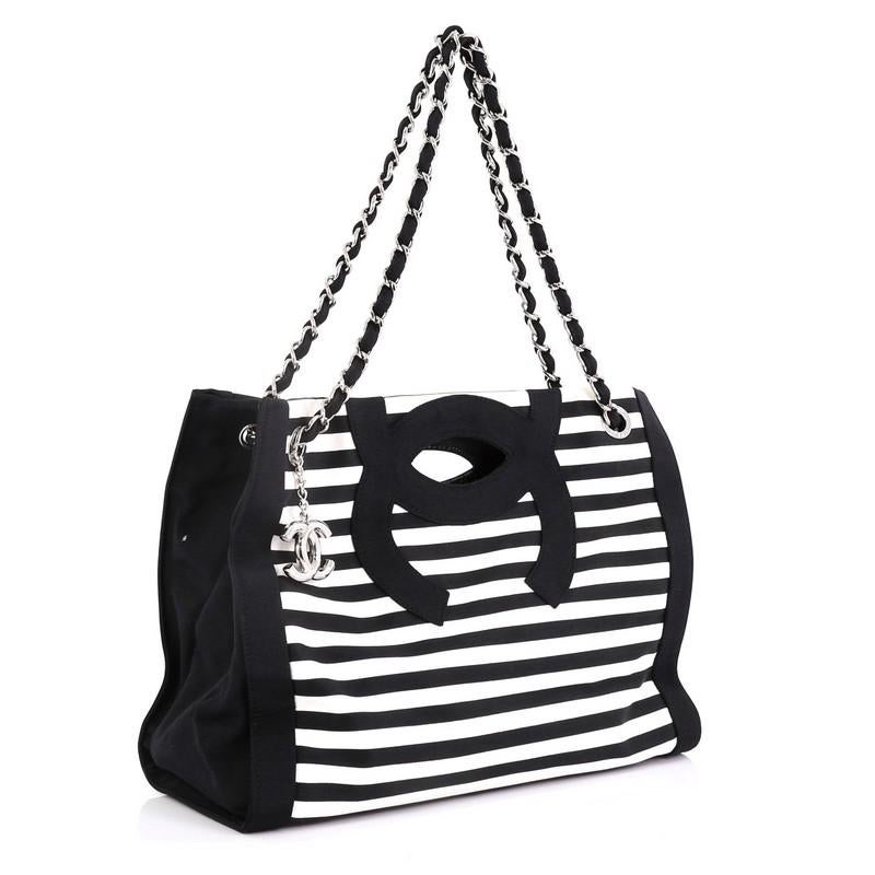 This Chanel Mariniere Chain Tote Striped Canvas Small, crafted in black and white striped canvas, features dual woven-in canvas chain straps, cutout top handles, and silver-tone hardware. Its wide open top showcases a black fabric interior with zip