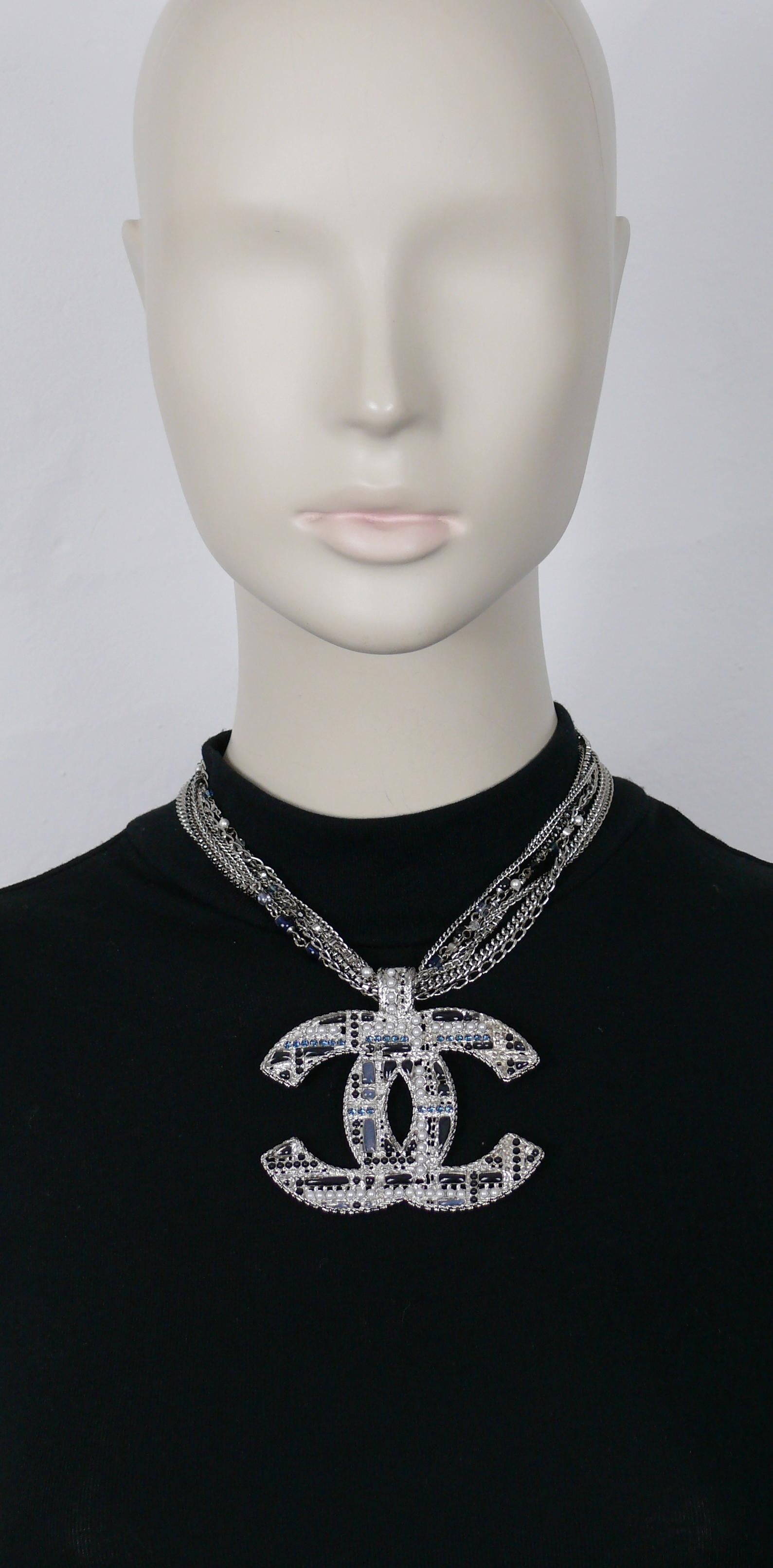 CHANEL silver toned multi-strand necklace featuring a massive CC pendant embellished with blue/grey poured resin, blue crystals, faux pearls and black beads.

Multi-strand intertwined chains embellished with black crystals, black/blue beads and faux