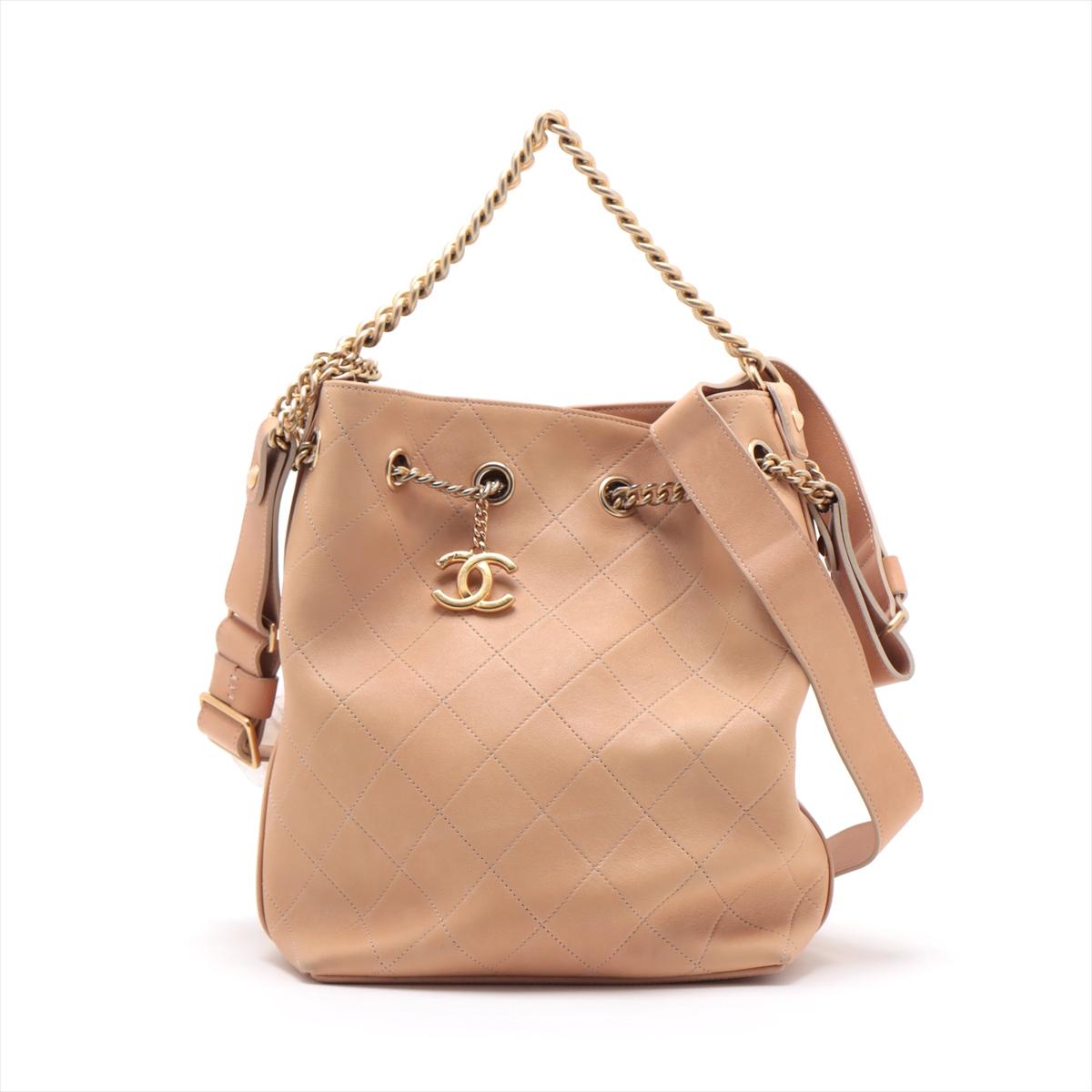 The Chanel Matelassé Drawstring Chain Two-Way Shoulder Bag in Beige is a sophisticated and versatile accessory that seamlessly merges classic elegance with modern functionality. Crafted with meticulous attention to detail, the iconic matelassé