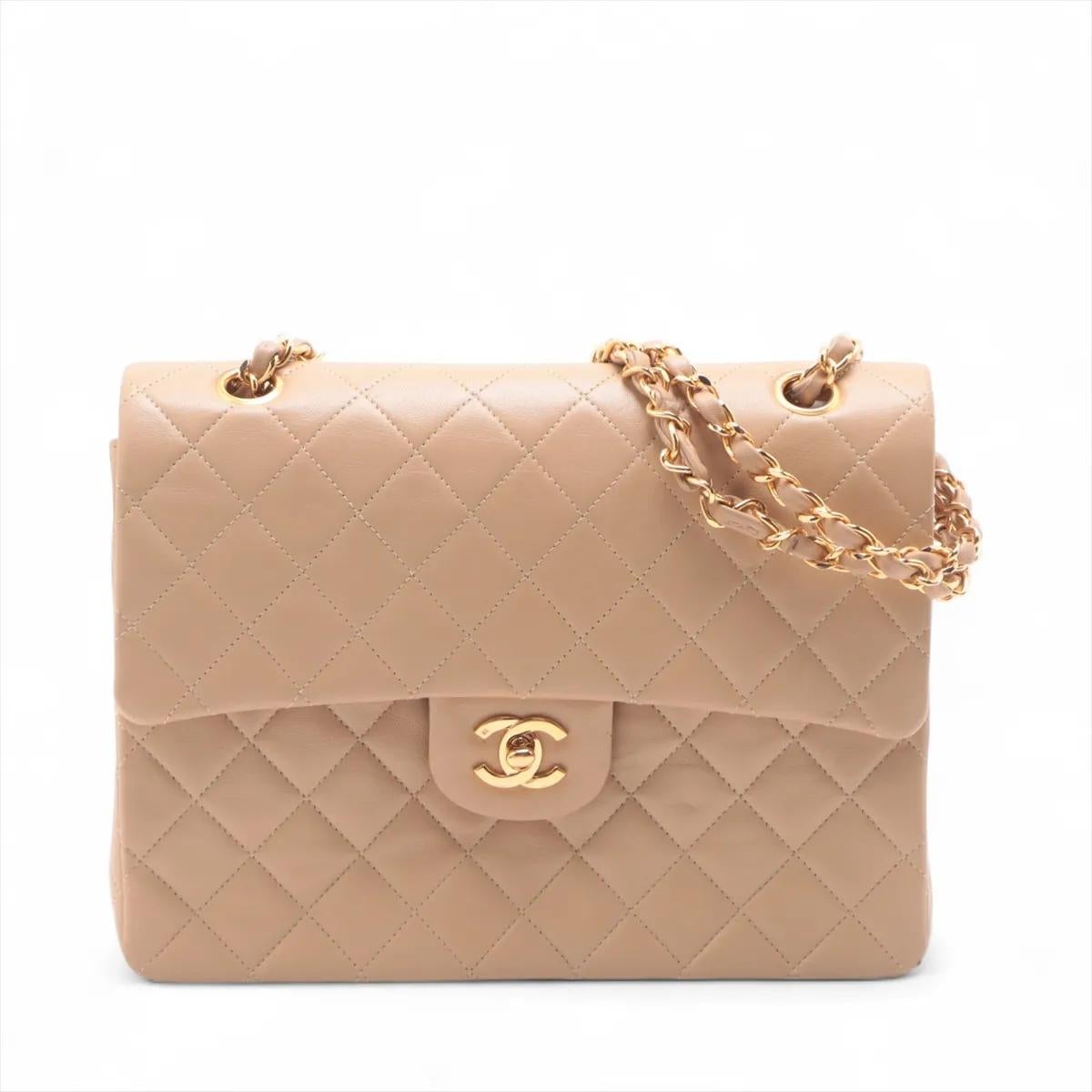 Le sac Chanel en cuir d'agneau matelassé à double rabat et double chaîne en beige est une pièce quintessentielle qui incarne l'élégance intemporelle et l'artisanat raffiné. Réalisé en cuir d'agneau souple et luxueux avec le motif matelassé