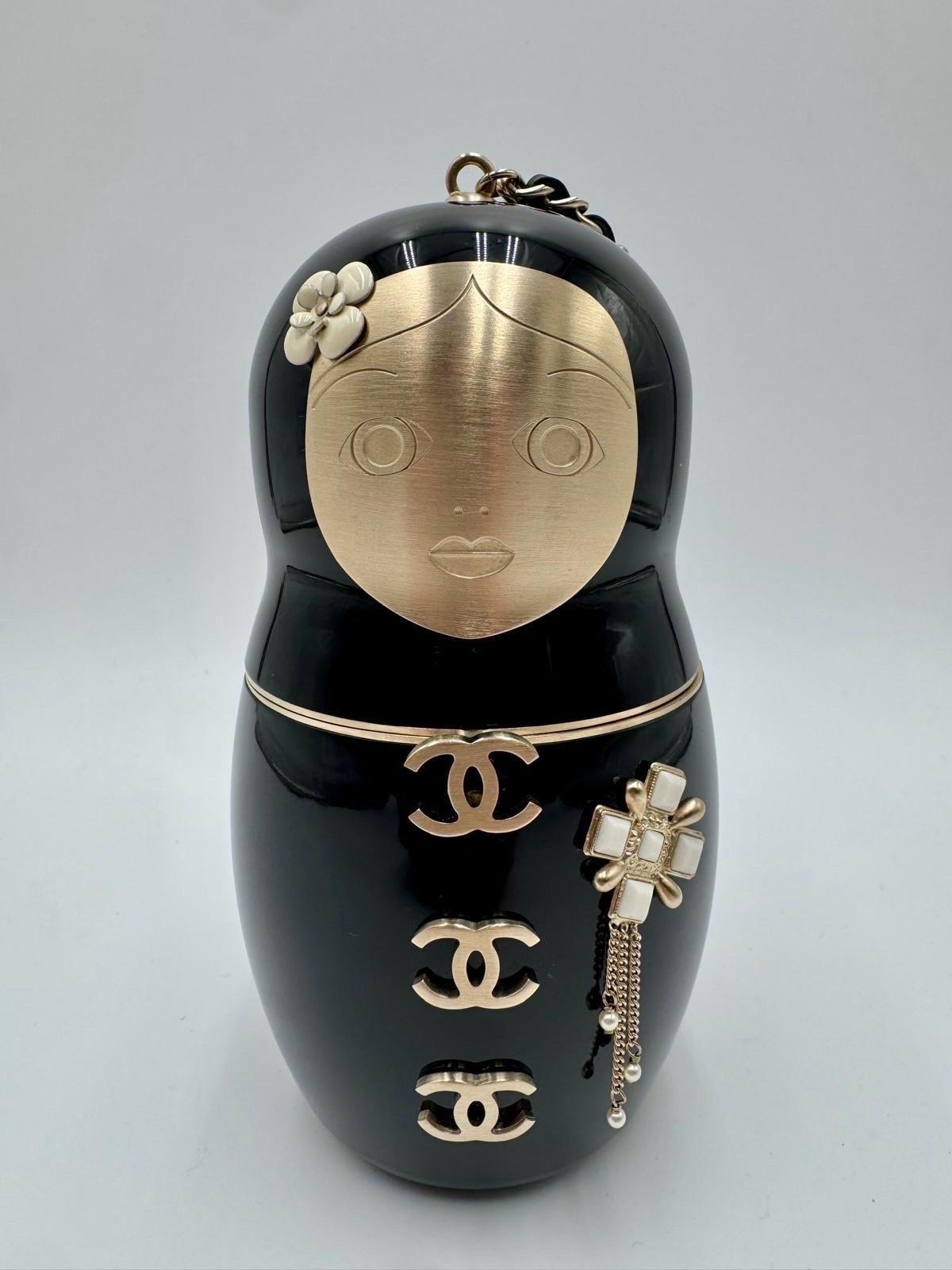 Esta rara e icónica Minaudière de Muñeca Matryoshka de Chanel es una auténtica pieza de coleccionista, inspirada en las tradicionales muñecas rusas de anidar. Confeccionado en plexiglás negro con herrajes dorados, este bolso de mano lleva los