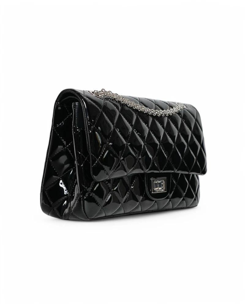 Sac de créateur Chanel, modèle Maxi Jumbo Reissue, en cuir verni noir fin avec des ferrures argentées. Ce modèle est doté d'une fermeture à double bouton et d'une fermeture à pivot externe, doublé intérieurement en cuir lisse ton sur ton avec des