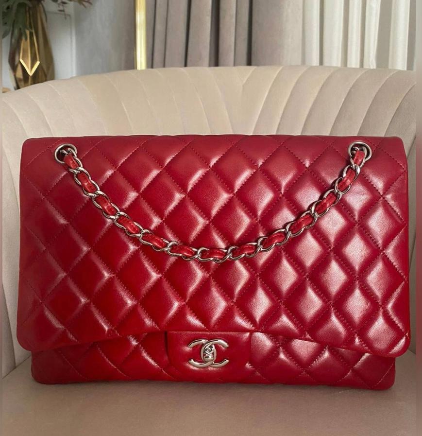 This Maxi Classic Single Flap bag is in red lambskin leather with silver shiny tone hardware and features a front flap with signature CC turn lock closure, half moon back pocket, and adjustable interwoven silver tone chain link and red leather