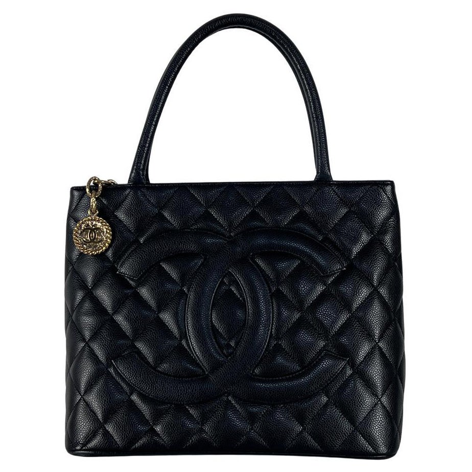 Magnifique sac à main CHANEL modèle Médaillon, réalisé en cuir de veau grainé noir, sublimé par une bijouterie dorée. Créé sous l'ère Karl Lagerfeld, ce modèle incarne la sophistication des années 2000, alliant allure urbaine et élégance