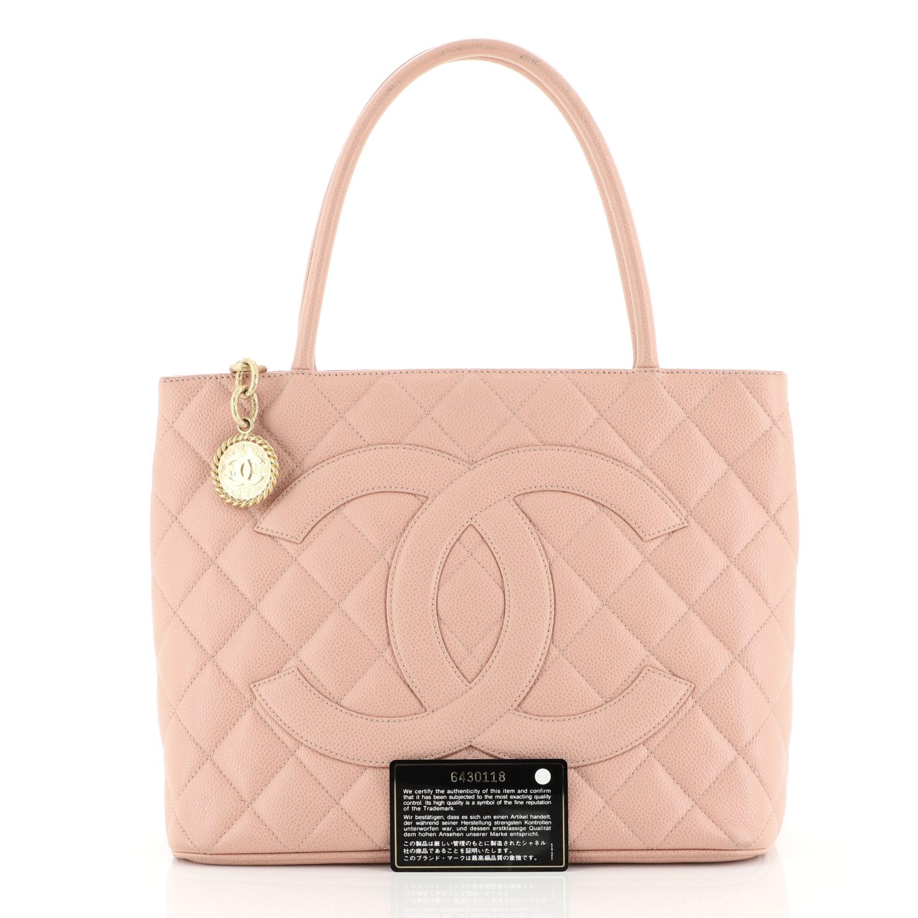 This Chanel Medallion Tote Quilted Caviar, crafted from pink quilted caviar leather, features dual rolled tall handles, oversized stitched CC logo, exterior back slip pocket, and matte gold-tone hardware. Its zip closure opens to a pink leather