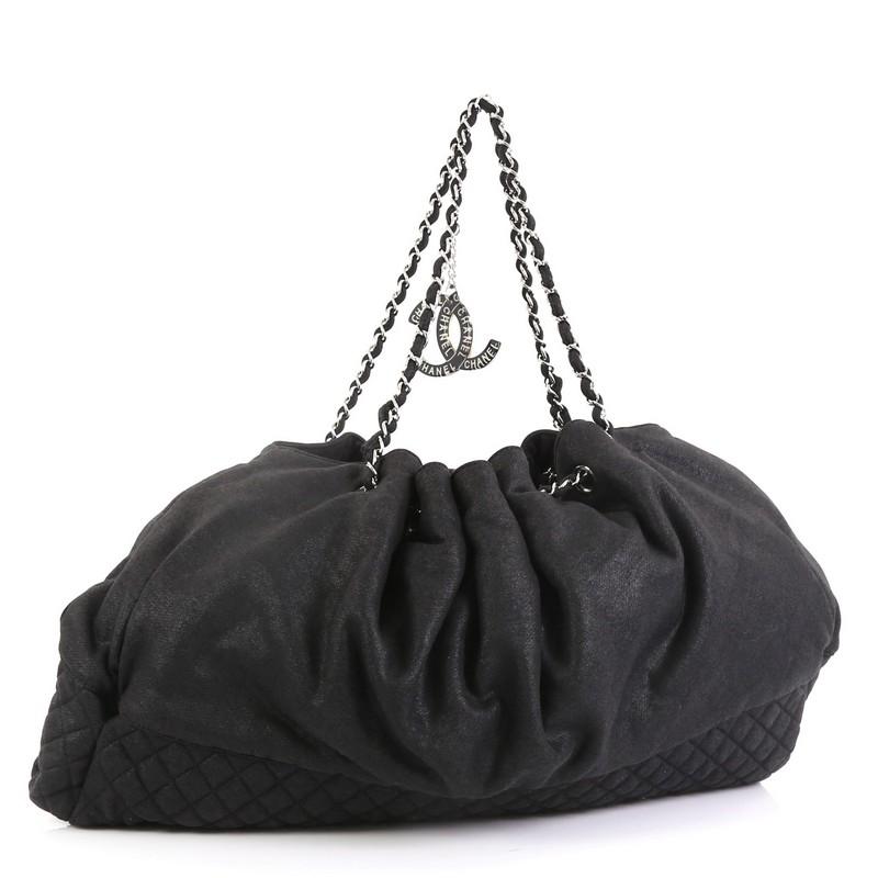 This Chanel Melrose Cabas Tote Jersey Medium, crafted from black jersey, features quilted diamond base, woven-in leather chain strap, and silver-tone hardware. Its drawstring top opens to a roomy silver silk interior with slip pockets. Hologram
