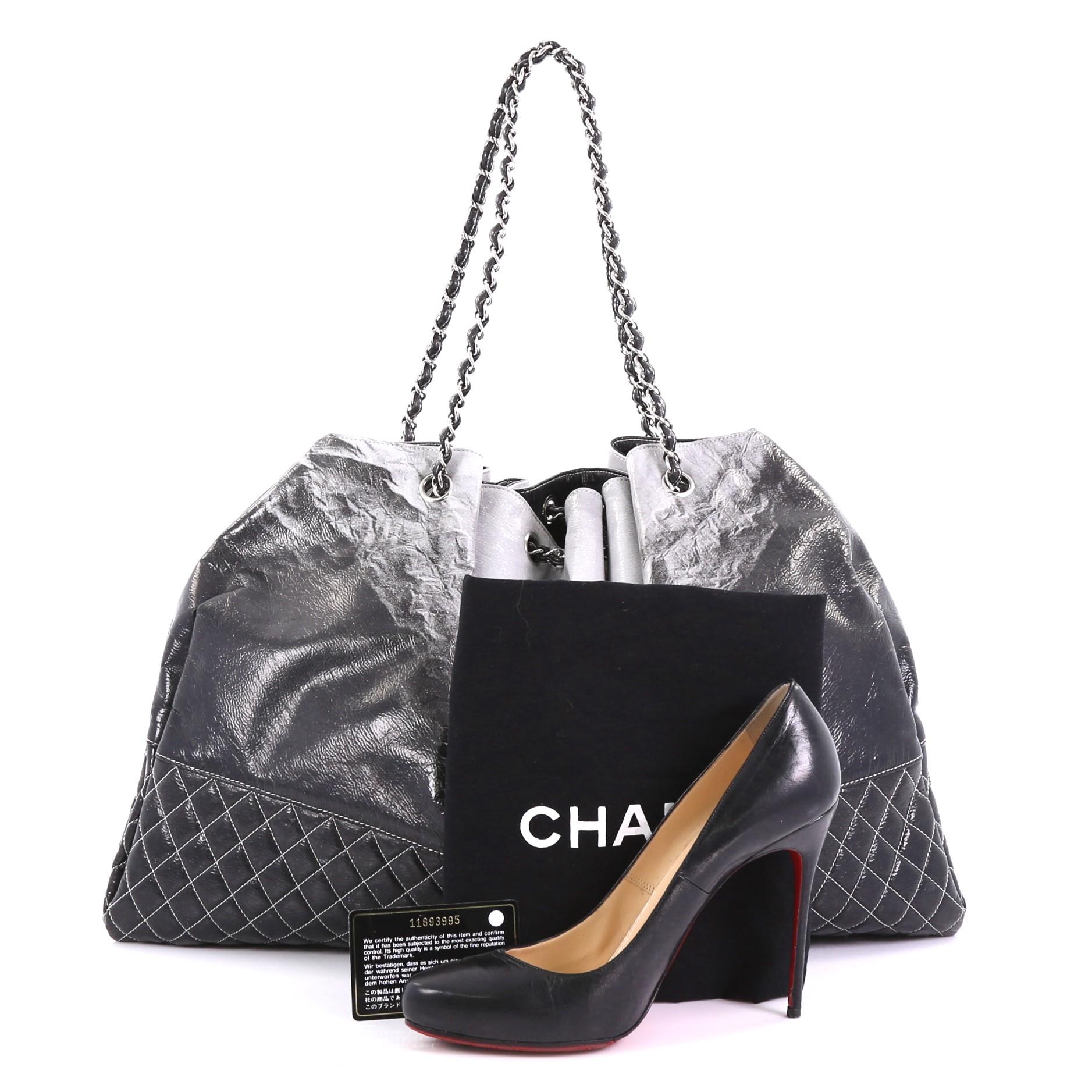 This Chanel Melrose Degrade Cabas Tote Patent, crafted in black and gray patent leather, features woven in leather chain link strap, pleated silhouette, and silver-tone hardware. It opens to a gray nylon interior with slip pocket. Hologram sticker