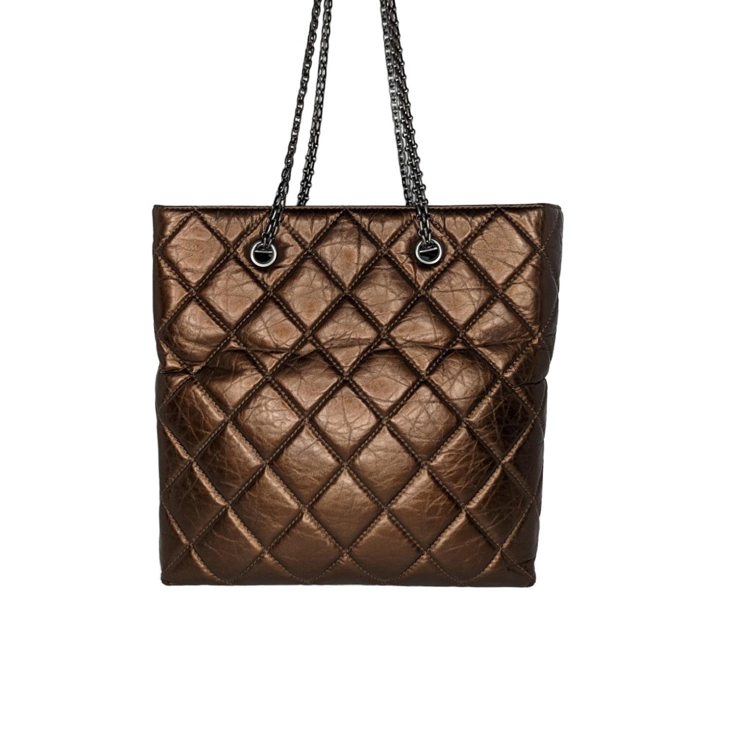 This exquisite tote is beautifully crafted of diamond quilted distressed aged calfskin leather in metallic bronze. The bag features bijoux ruthenium tightly linked chain shoulder straps and a ruthenium squared mademoiselle turn-lock. This opens to a