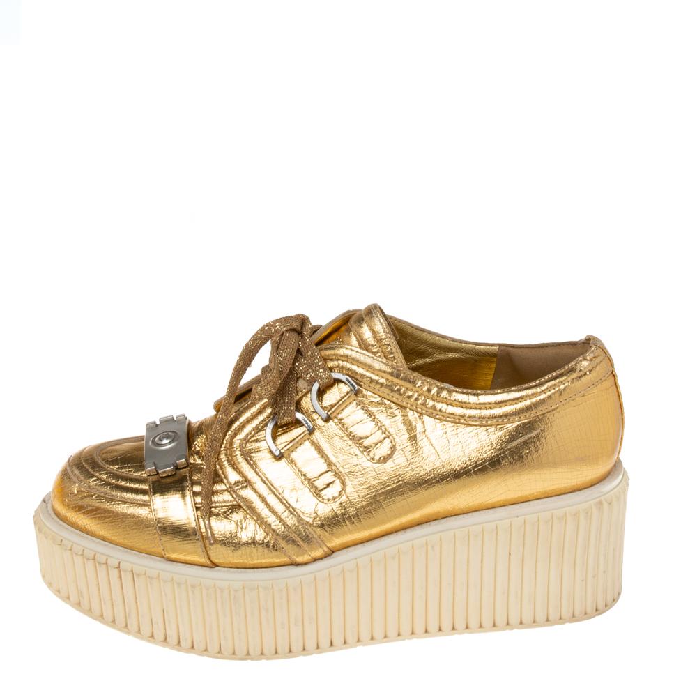 How glamorous are these sneakers from the House of Chanel! They are created using metallic-gold distressed foil leather on the exterior. They showcase platforms, lace-up fastenings on the vamps, and silver-tone hardware. These stunning Chanel