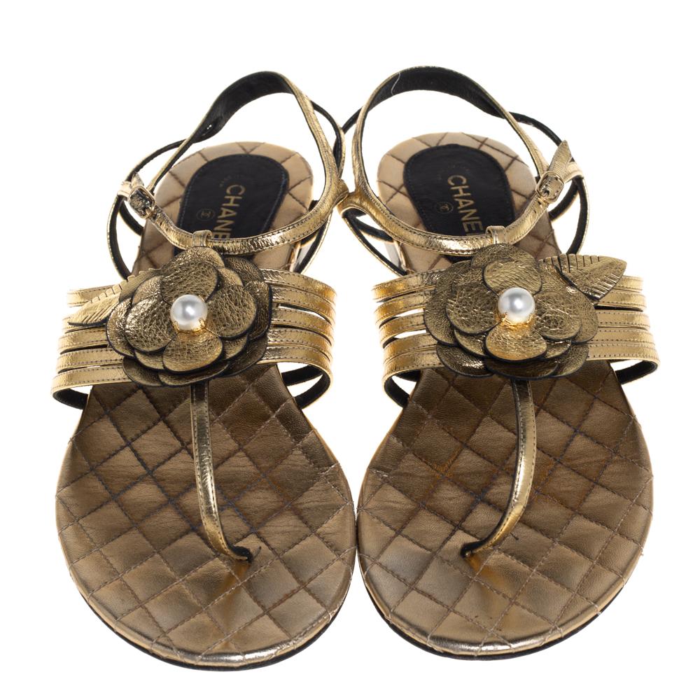 Beauty flows out of these ankle strap sandals from Chanel! Wonderfully made, these metallic gold sandals are crafted from leather and feature a thong design with the signature Camellia flower detailing on the mid strap. They are endowed with