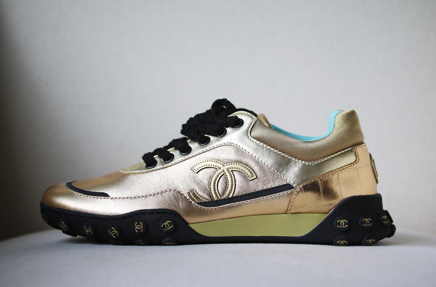 Chanel's trainers are embellished with a playful logo spelling the label's name - the metallic gold colors really pop against the black contrast. The mix of rubber, smooth leather and textured fabric creates a cool tactile contrast. Thanks to the