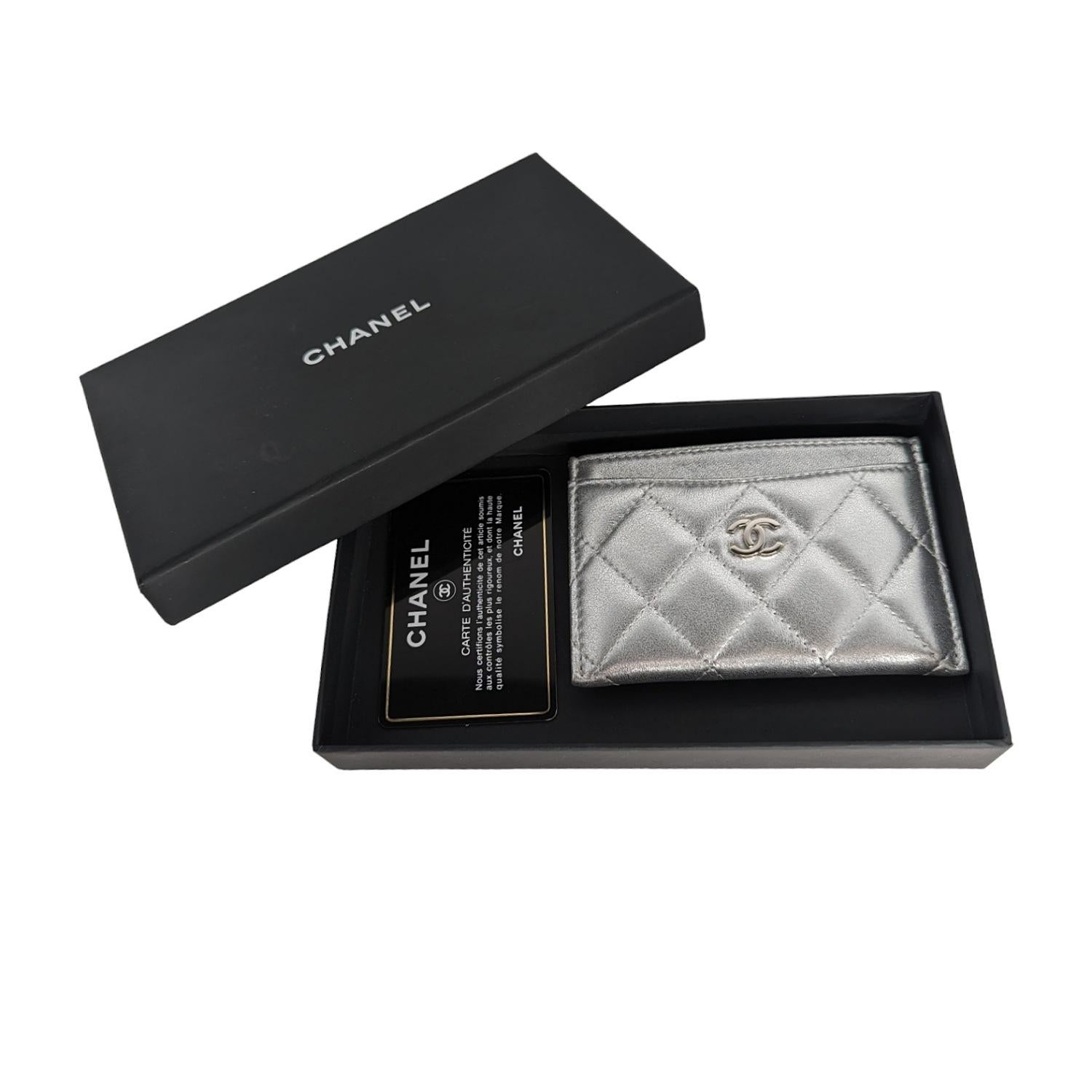 This stylish holder is crafted of luxurious metallic diamond quilted lambskin leather in silver with a silver frontal Chanel CC logo. The exterior features three card slots with beige fabric interiors and a main compartment in the center with a