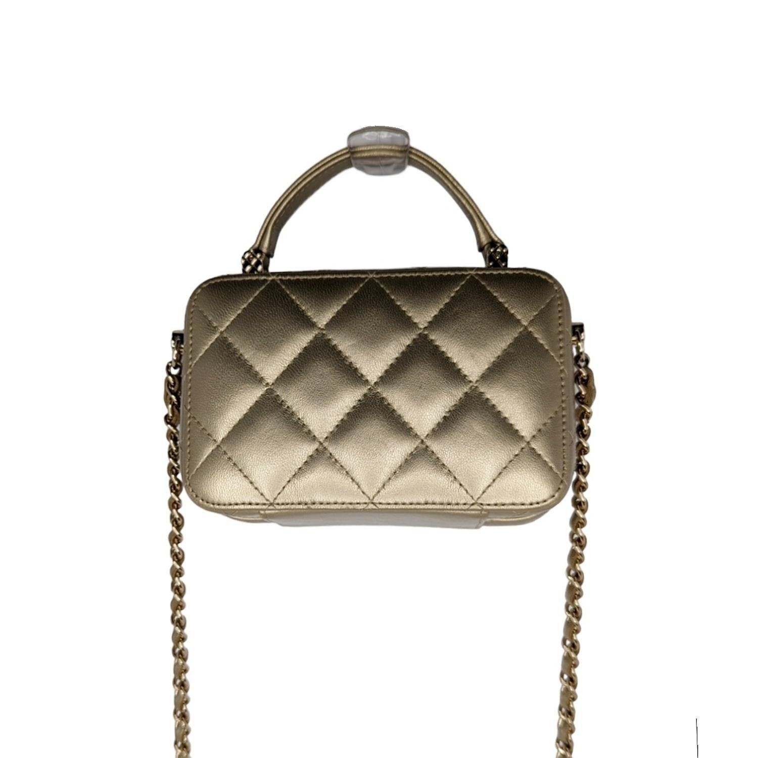Chanel Metallic Quilted Top Handle Vanity Case in Gold. This chic stylish Chanel bag is crafted of luxurious lambskin leather. The elegant shoulder bag features the signature gold and threaded leather chain with a shoulder pad. Retail