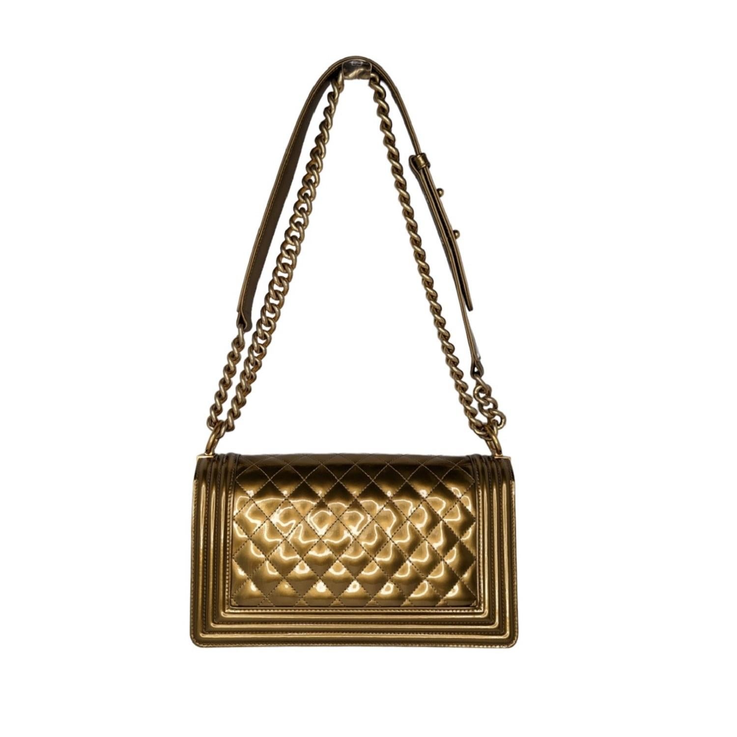 This stylish shoulder bag in the larger size is crafted of glossy patent leather in gold framed by a linear quilting. The bag features a polished gold tone chain link shoulder strap with a leather shoulder pad and a unique squared polished gold tone