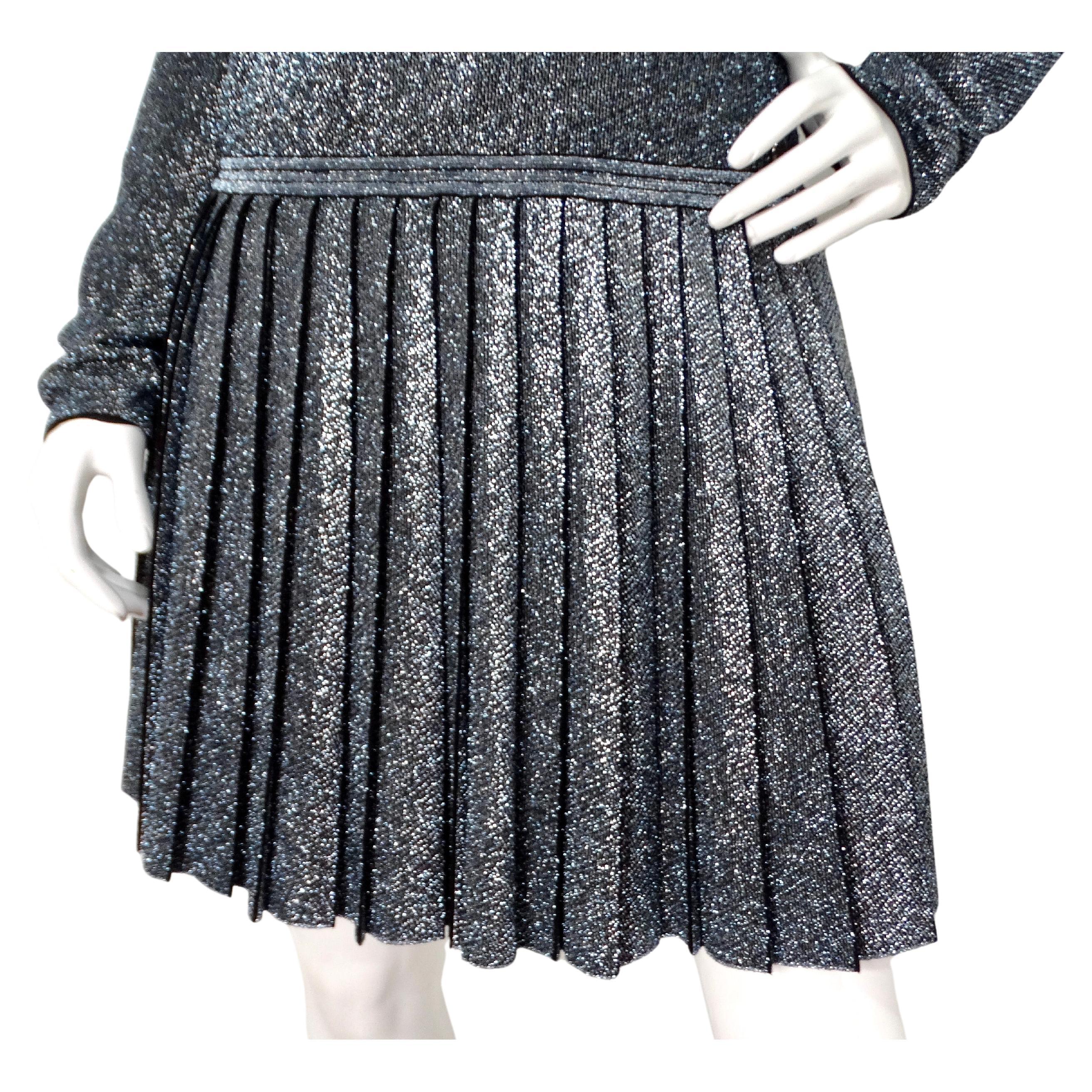 La robe à manches longues plissées métallisées de Chanel est un superbe exemple d'élégance haute couture teintée d'une touche contemporaine. Confectionnée dans une étoffe métallique argentée scintillante, cette robe respire la sophistication et la