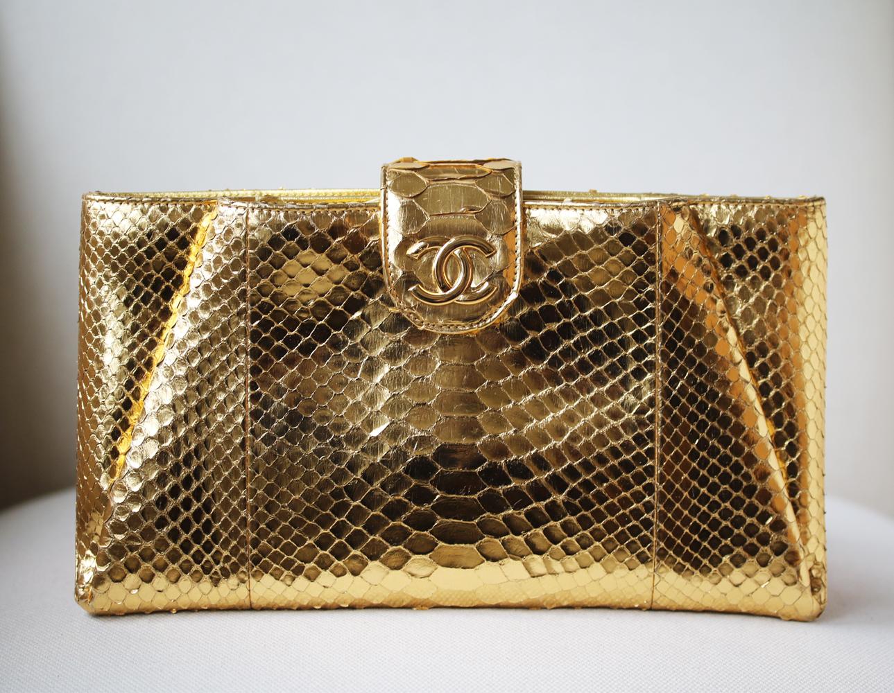 Chanel Metallic Python Clutch. Features metallic-gold python-skin. Gold CC hardware, and metallic-gold leather lining. Two top zip compartments. Zip interior pocket and a flat interior pocket. Made in Italy. Does not come with a dustbag or box.