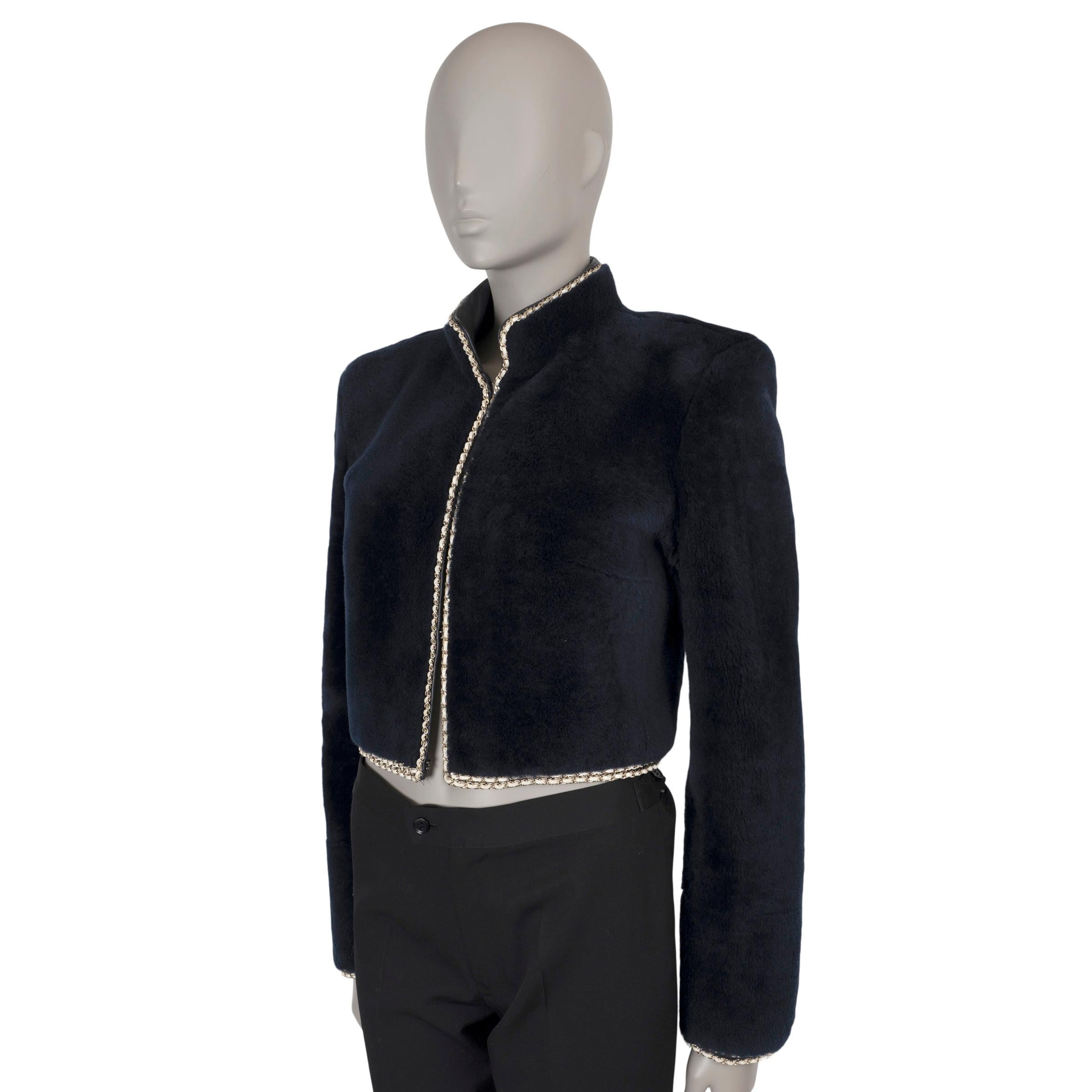 This 100% authentic Chanel jacket in midnight blue shearling fur embodies luxurious sophistication. It features a cropped, boxy silhouette with a high collar and a striking metallic gold leather interwoven gold-tone chain trim for a touch of iconic