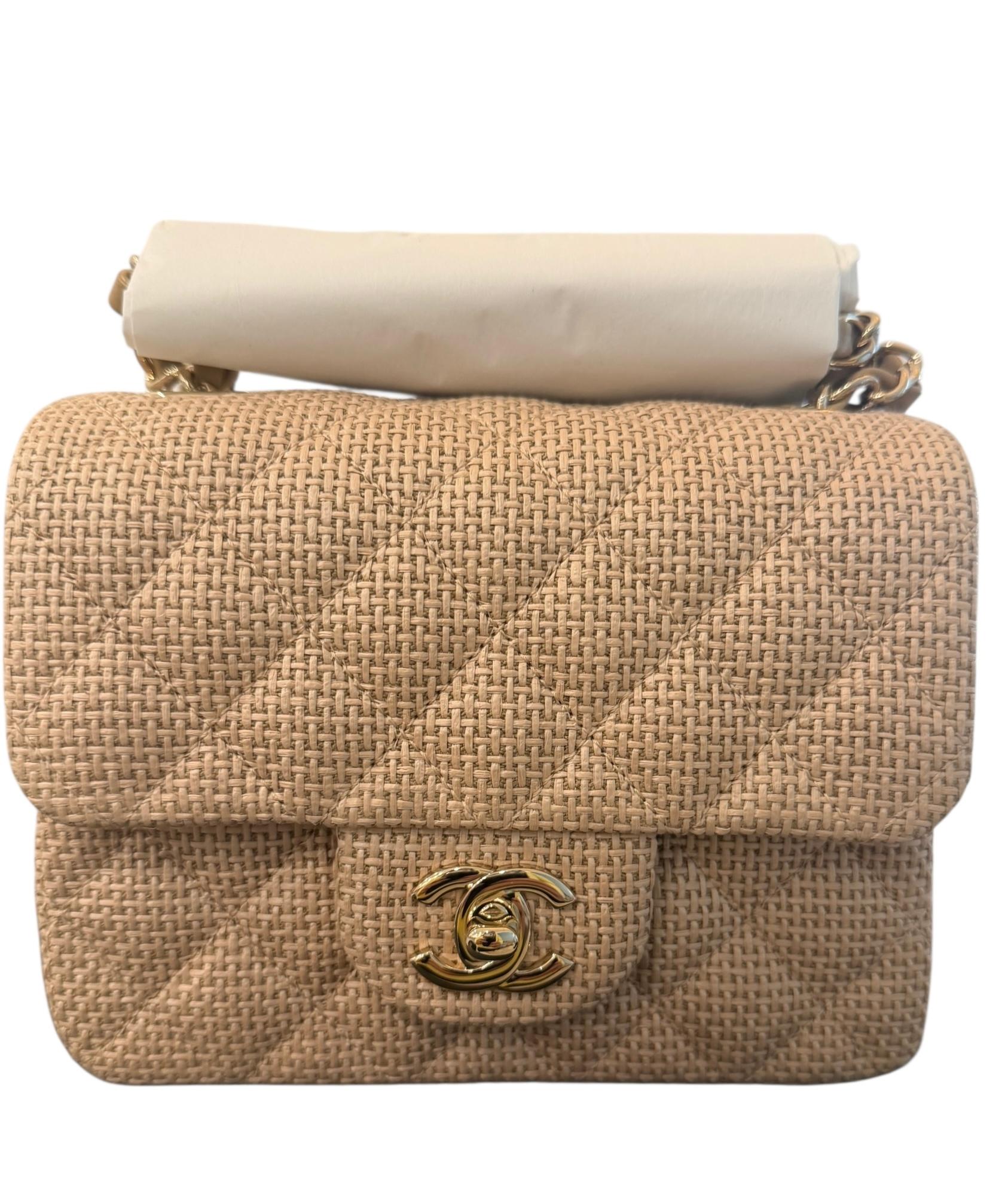 Questa Mini Classic Flap Bag in rafia beige scuro con finiture in oro chiaro è dotata di una patta frontale con chiusura a girello CC e di una tracolla singola intrecciata in oro chiaro e pelle beige scuro.

Misure approssimative: 6,5