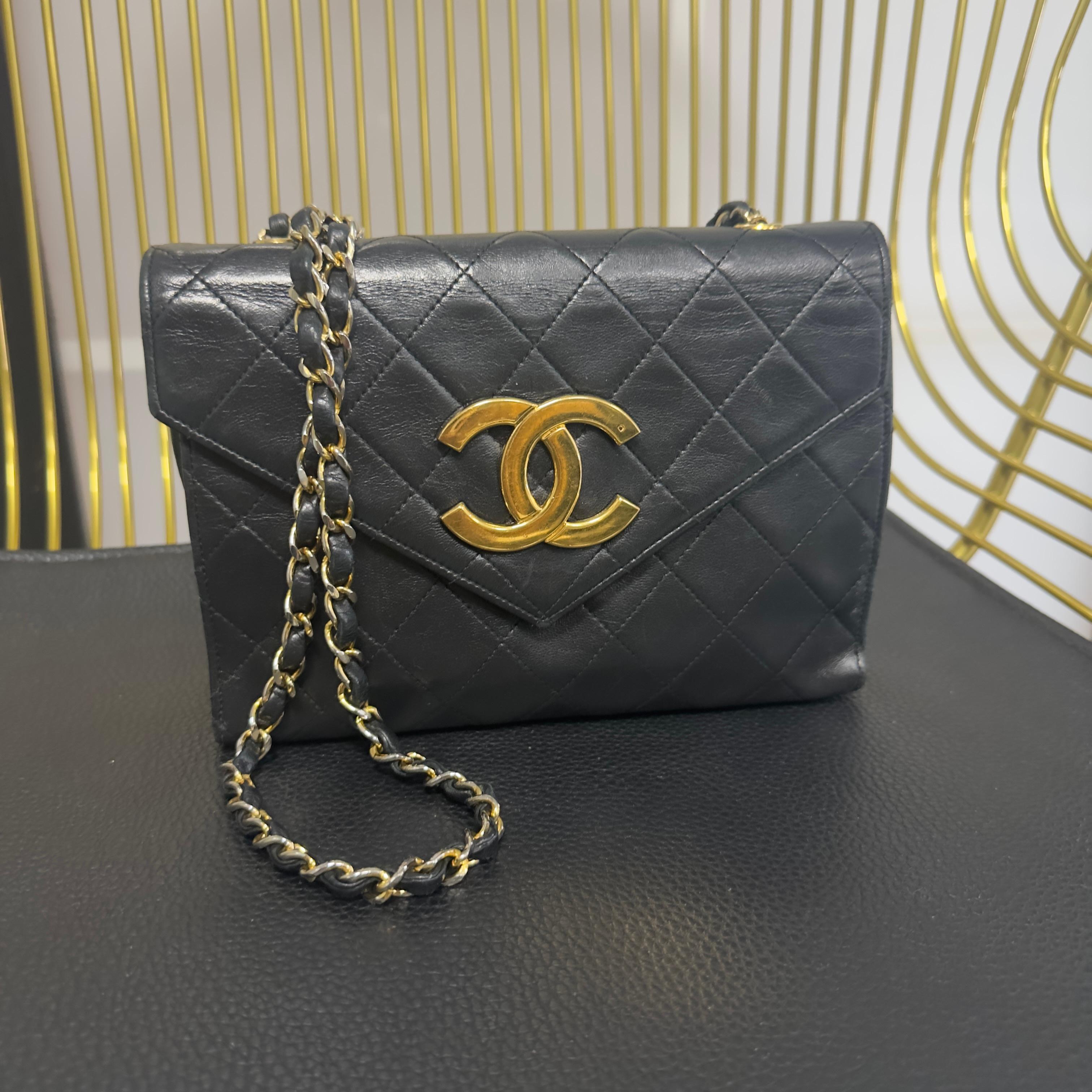 Un’autentica icona Chanel degli anni ’80, rara e ricercatissima: mini borsa a tracolla in pelle di agnello nera, caratterizzata dal grande logo CC dorato in metallo lucido, uno dei dettagli più iconici delle produzioni vintage della