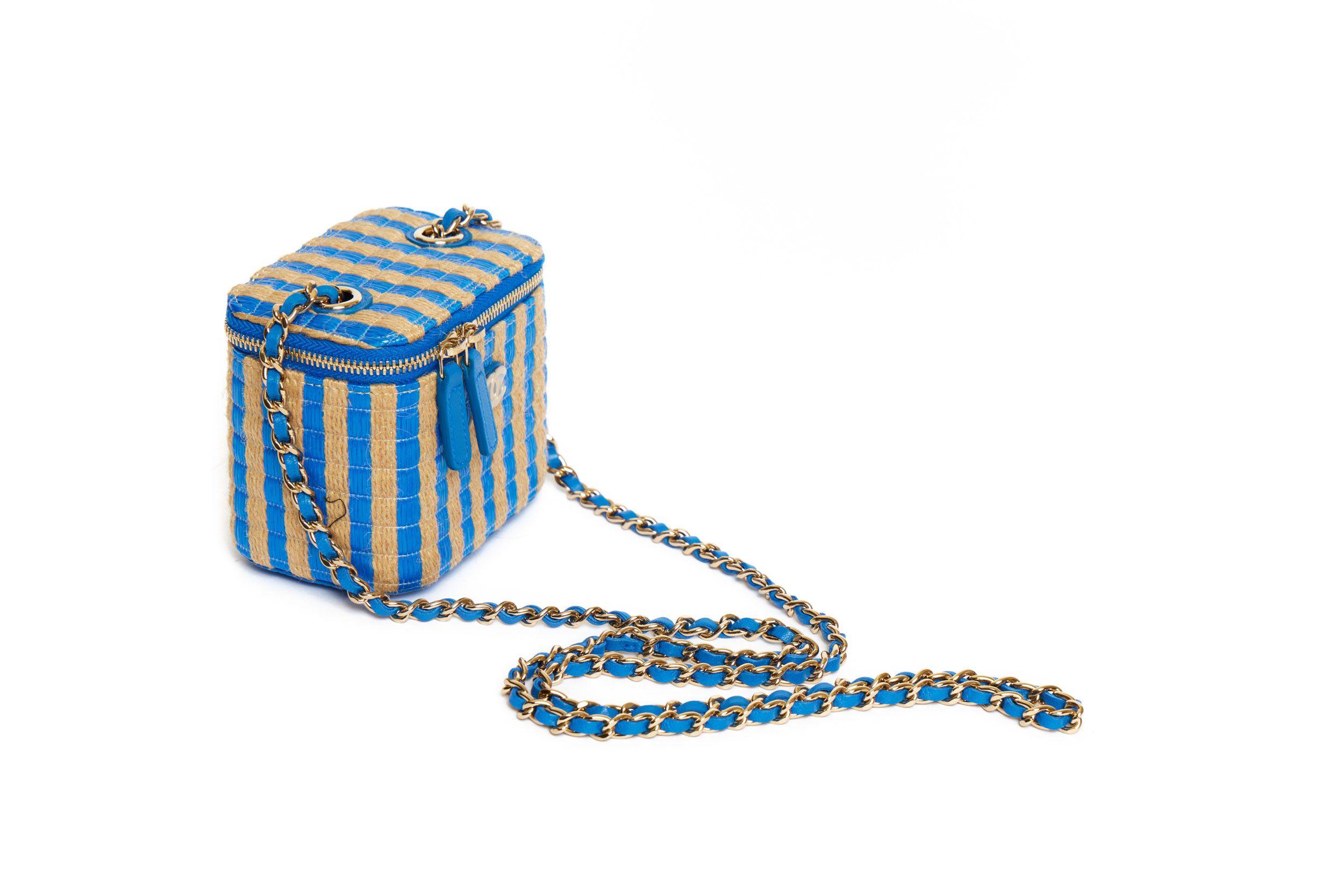 Mini Chanel Raffia Vanity bag with blue stripes from the 2020 collection. It’s a crossbody bag and the shoulder drop of the leather-threaded gold chain is 22’. On front of the bag is a small CC logo which is still covered in plastic. The interior is