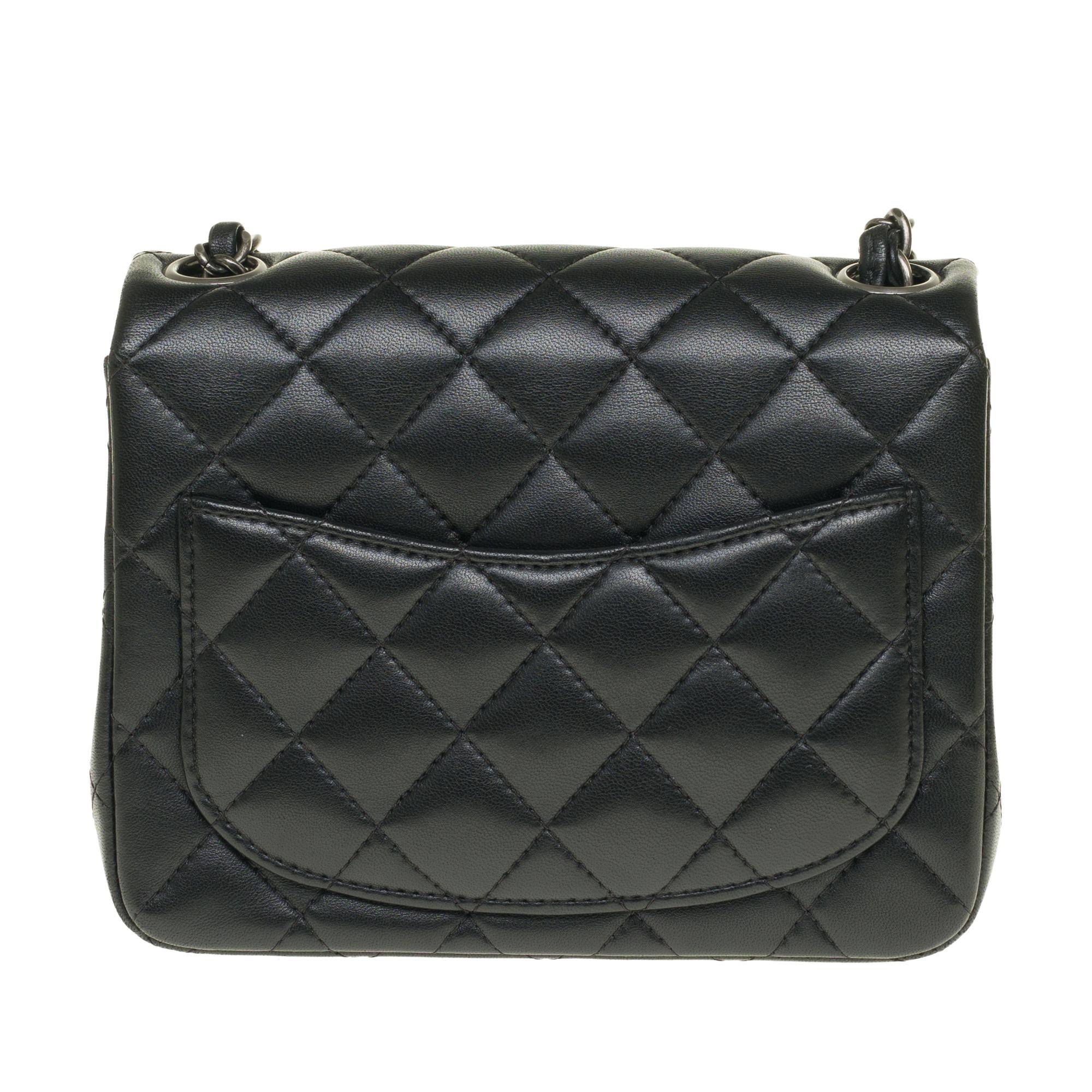 Beautiful Chanel Mini Timeless handbag in black nappa leather, chain handle intertwined with black leather allowing a hand or shoulder or shoulder strap.

Silver metal flap closure.
A patch pocket on the back of the bag.
Lining in black leather, one