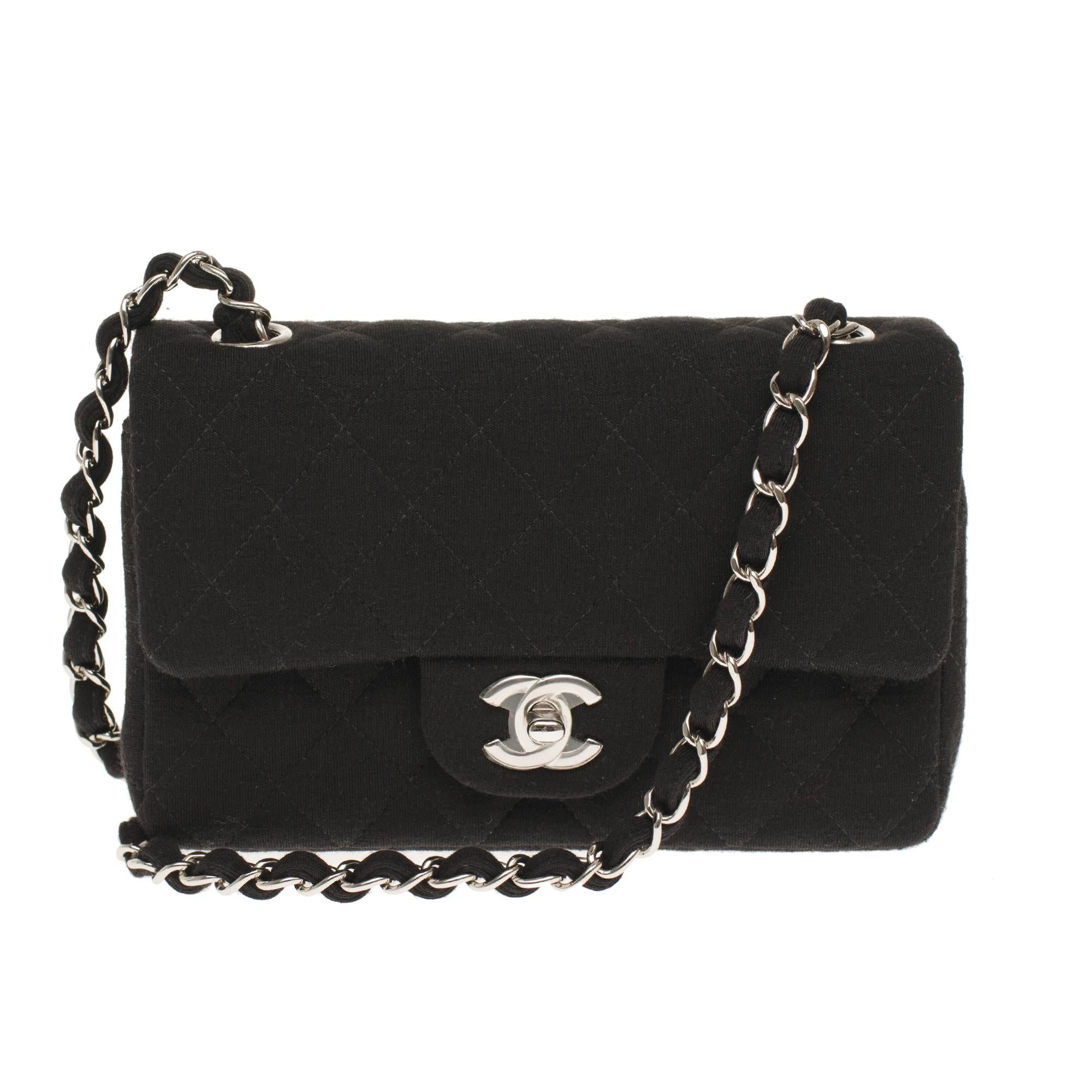 Gorgeous Mini Chanel Timeless/ Classic in black canvas, silver metal trim , a silver metal chain handle intertwined with black canvas allowing a hand or shoulder or shoulder strap.

Flap closure with silver metal turnstile.
A patch pocket on the