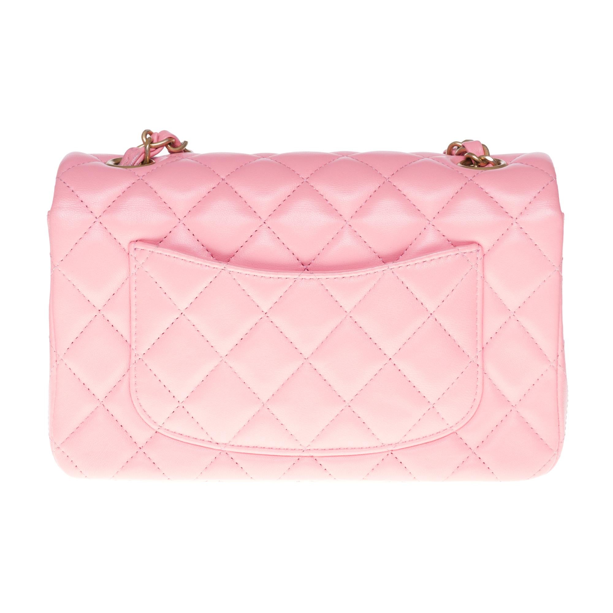 The superb shoulder bag Chanel Mini Timeless in pink quilted leather, gold metal hardware, silver metal chain handle intertwined with pink leather allowing a shoulder or shoulder strap.

Closure by flap.
A patch pocket on the back of the bag.
Lining