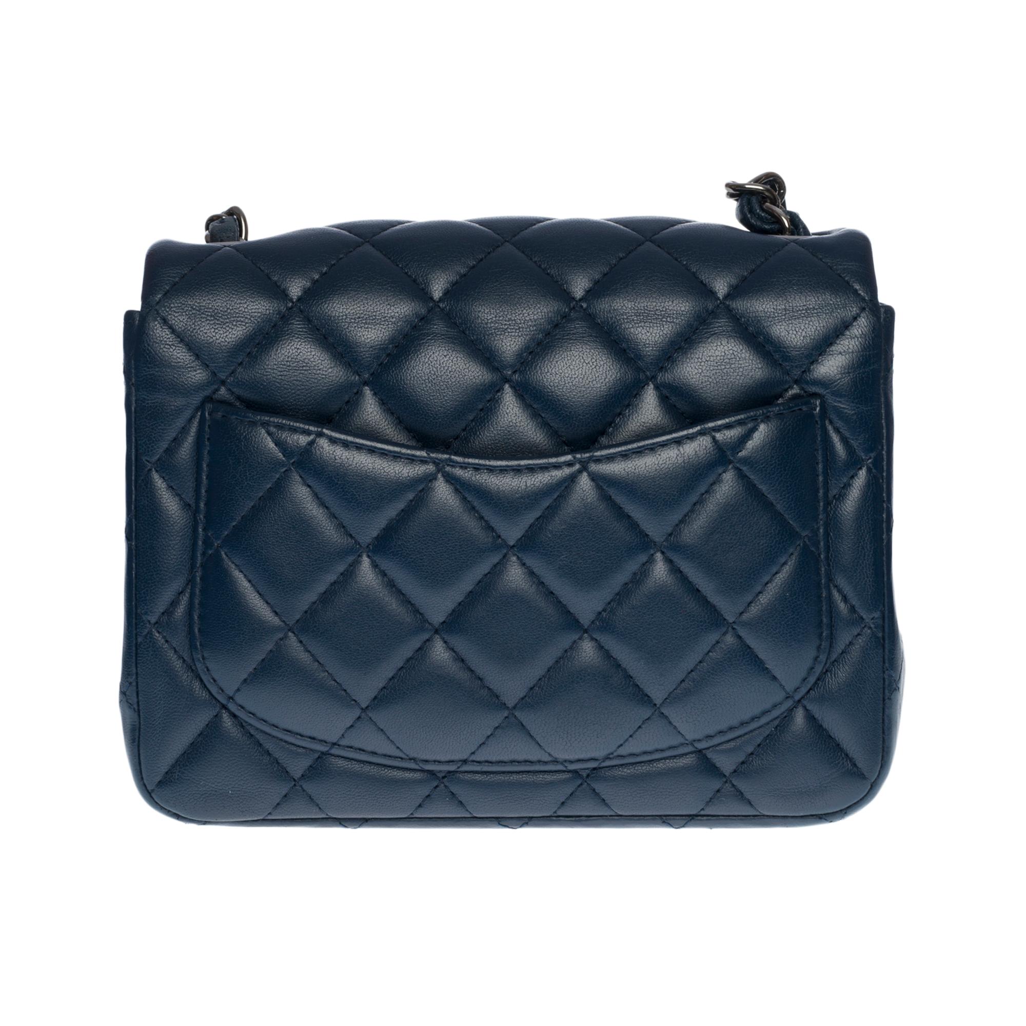 Stunning Chanel Mini Timeless Flap bag in dark blue quilted leather, silver metal hardware, a silver metal chain interlaced with dark blue leather for a shoulder and crossbody support

Silver metal flap closure
A patch pocket on the back of the