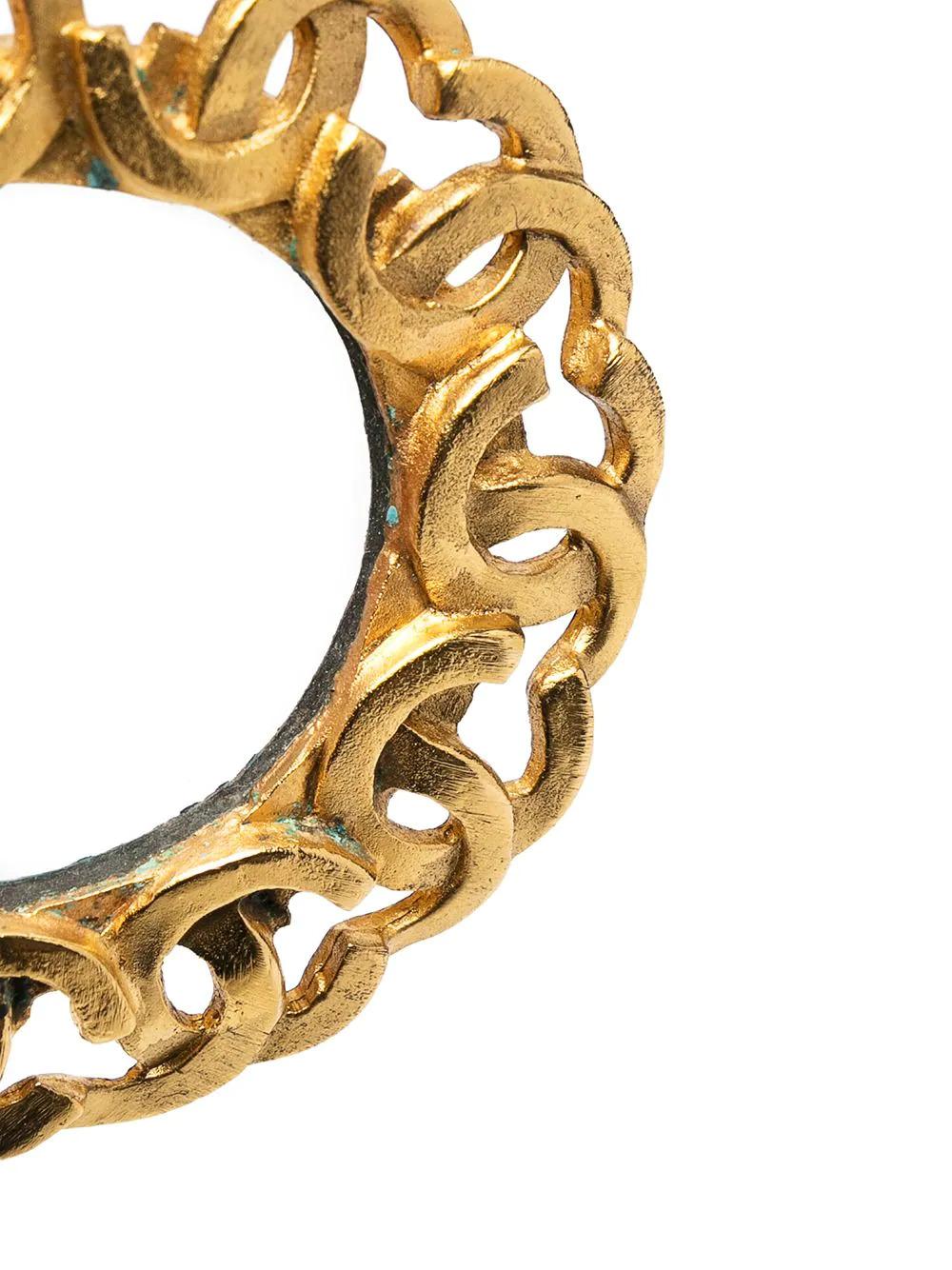 Un porte-clés vintage qui joue avec les logos en trompe-l'œil dans le plus pur style Chanel. Ce porte-clés Chanel est plaqué or et comporte un anneau de monogrammes tessellés pour former une chaîne.

Couleur : Or, clair

Matériau : Verre,