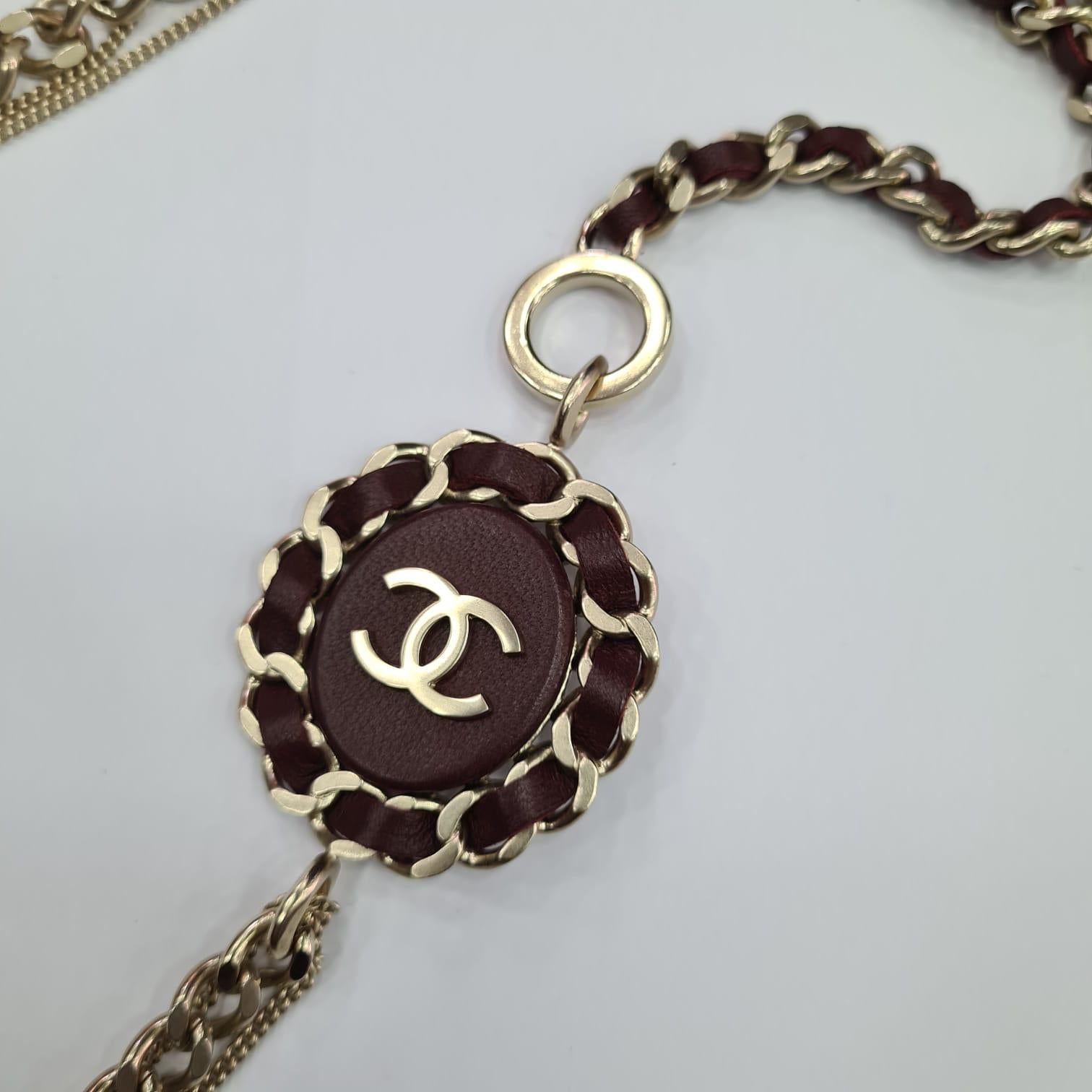 Chanel multi-chain long necklace with the iconic CC logo affixed on a bordeaux resin round. The silver tone chain is intertwined with bordeaux leather. It's hallmarked 