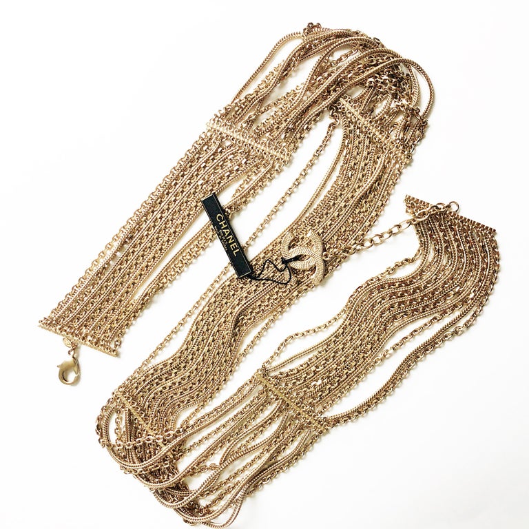 Authentic, NWT/NOS Chanel Multi-Chain Belt with CC Charm, from the 07P collection. Made from gold metal, one can wear this w/the clasp & CC logo charm facing front, back or wear the piece as an over-the-top necklace. It measures 34in L x 2in H with